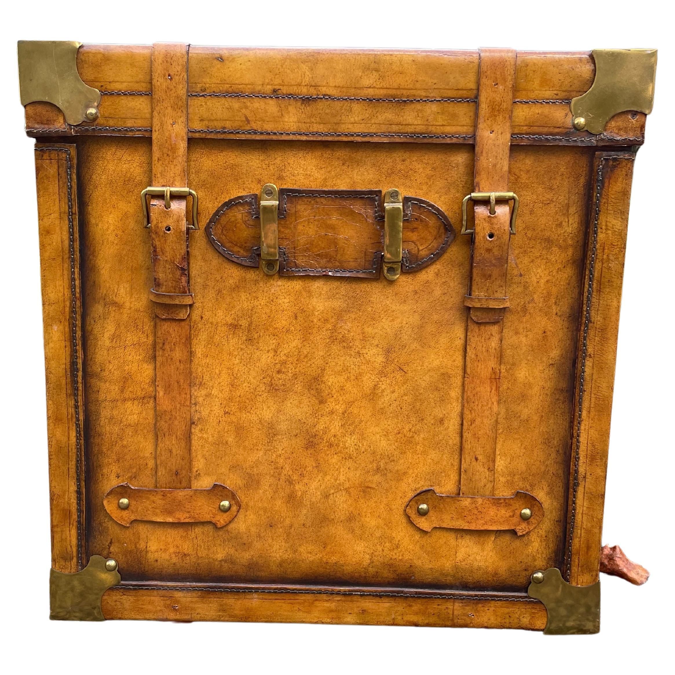 Handsome designer side table in the form of a leather trunk, having leather handles and straps, brass corners and knuckles. Note that the trunk doesn't open.
