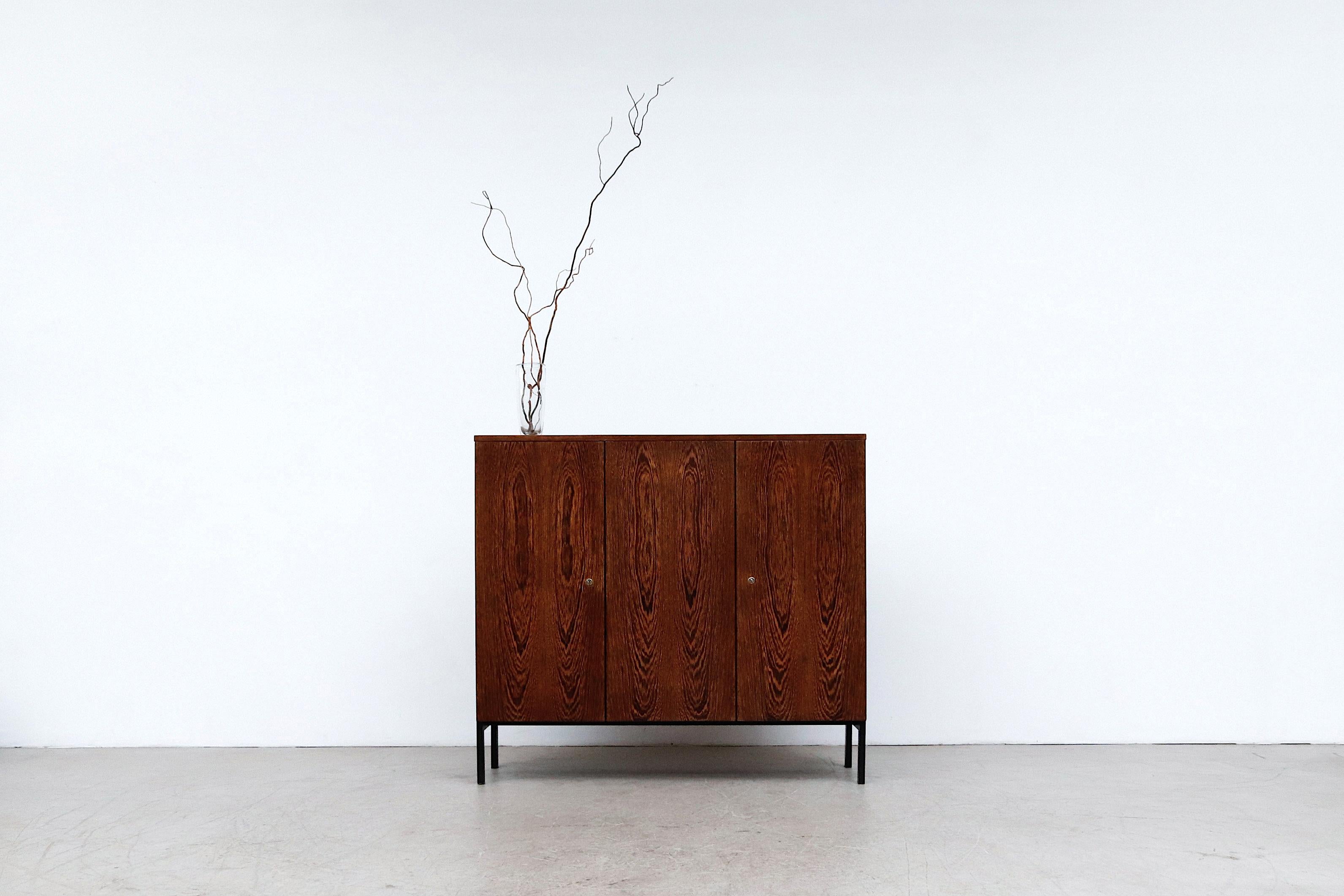 Handsome Tall Martin Visser wenge sideboard. Beautiful sideboard and room divider, as it is finished on the back. Cabinet has 3 doors, white formica shelves and black enameled metal legs. Left door lock is missing the key, but there is a magnetic