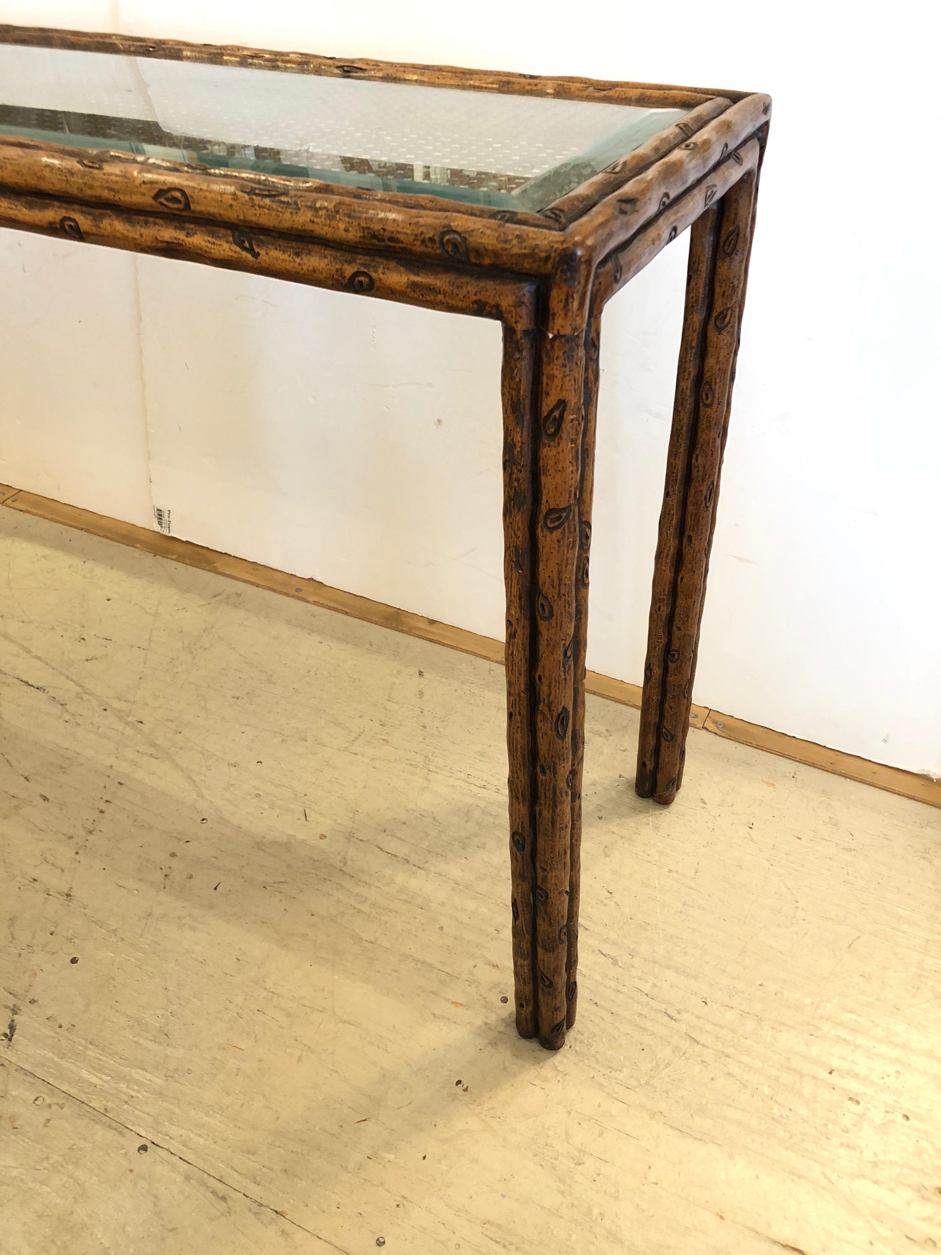 Very stylish console table having an earthy faux bois frame and handsome brown caned top covered with glass.