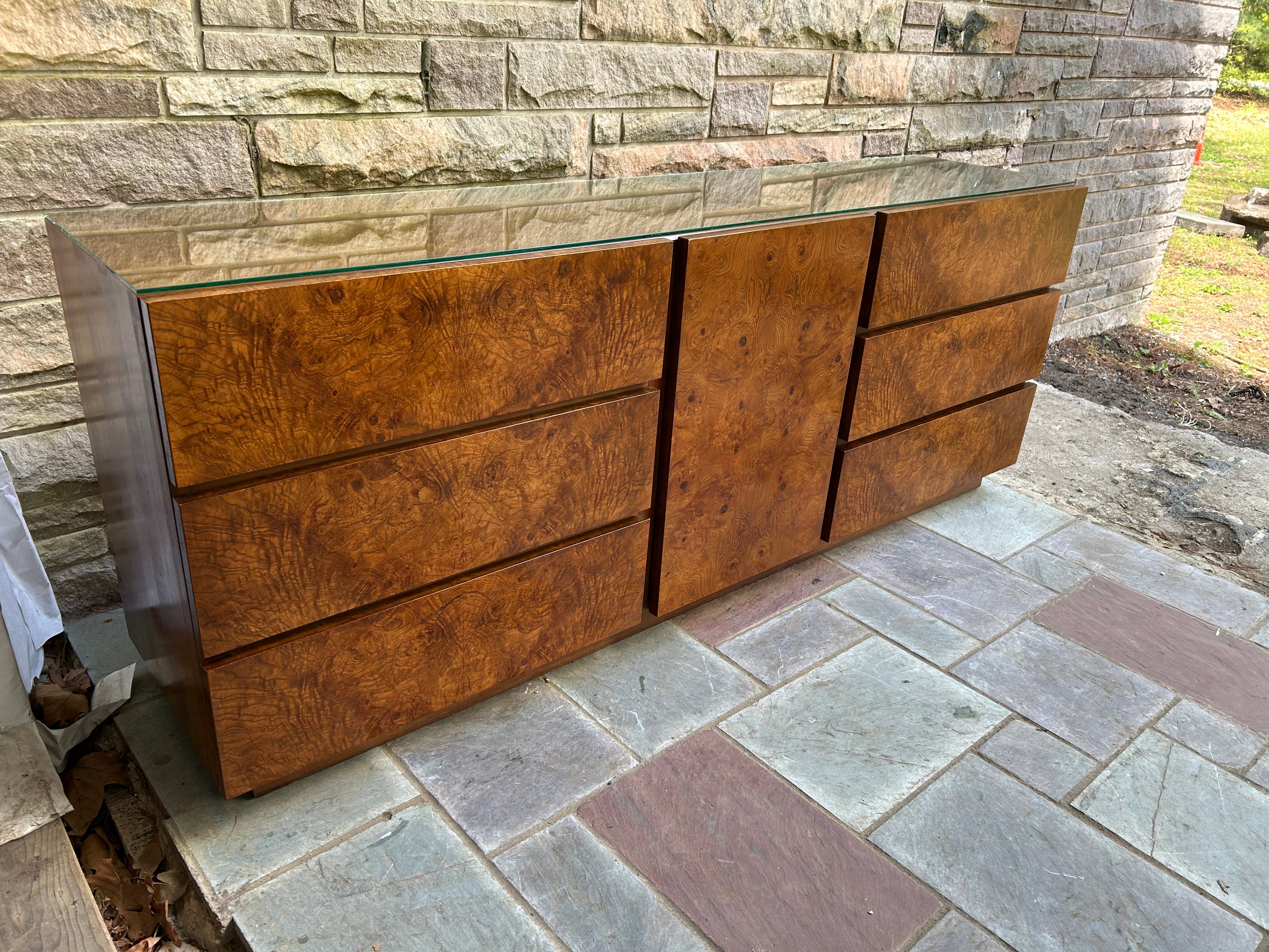 An outstanding Milo Baughman style Mid-Century Modern burl wood long dresser or credenza by Lane Furniture. The dresser features stunning wood grain and sleek mid-century design. It offers ample storage, with nine deep drawers. The original label is