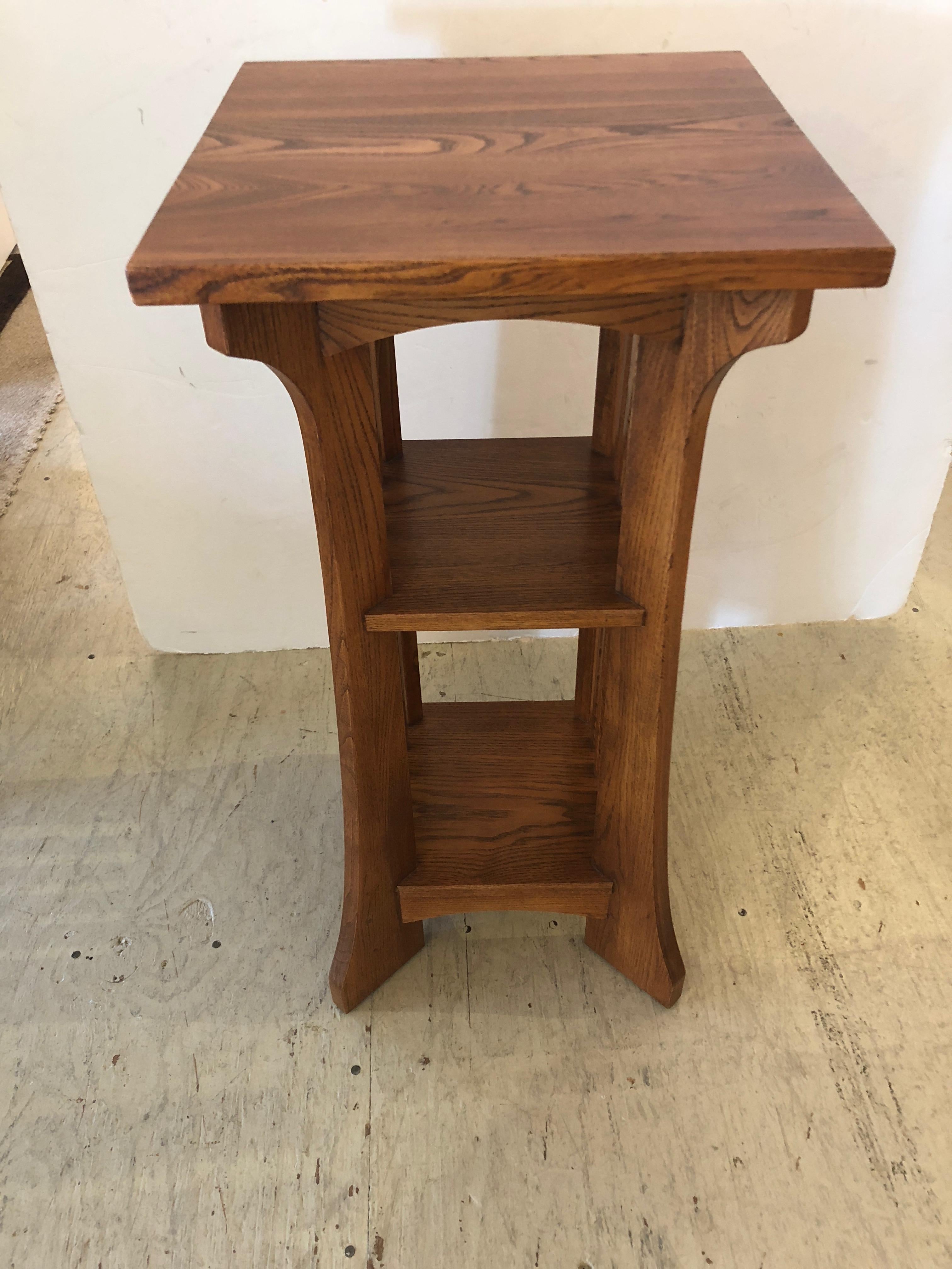 Handsome oak side table in the classic Arts & Crafts style having two shelves, beautiful grain on top, and slightly splayed feet.