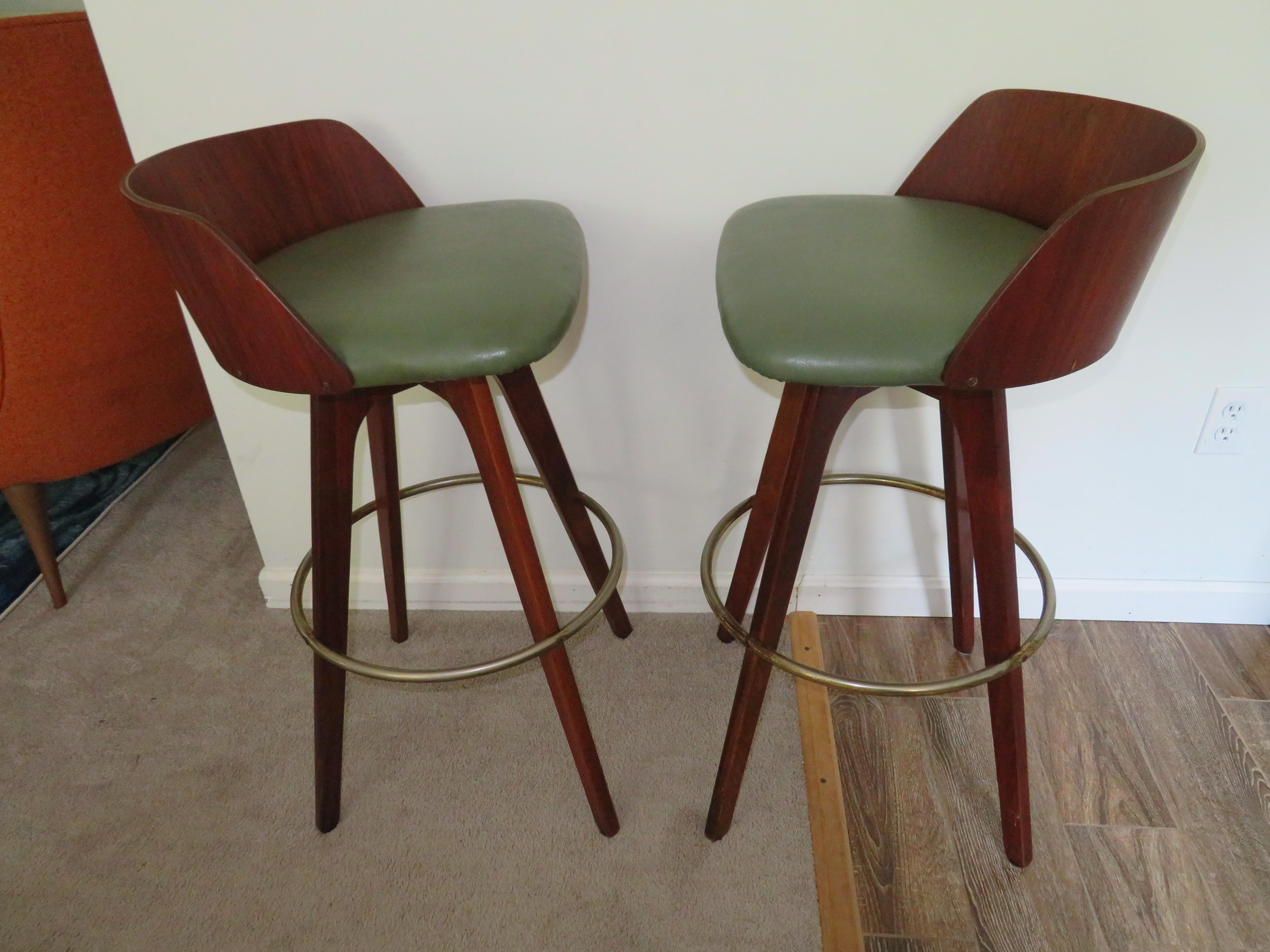 Handsome pair of walnut barrel back bar stools. Bent walnut backs and solid legs created by Chet Beardsley. Brass plated foot rings show some normal wear. These are quite comfortable to sit in and they do swivel.