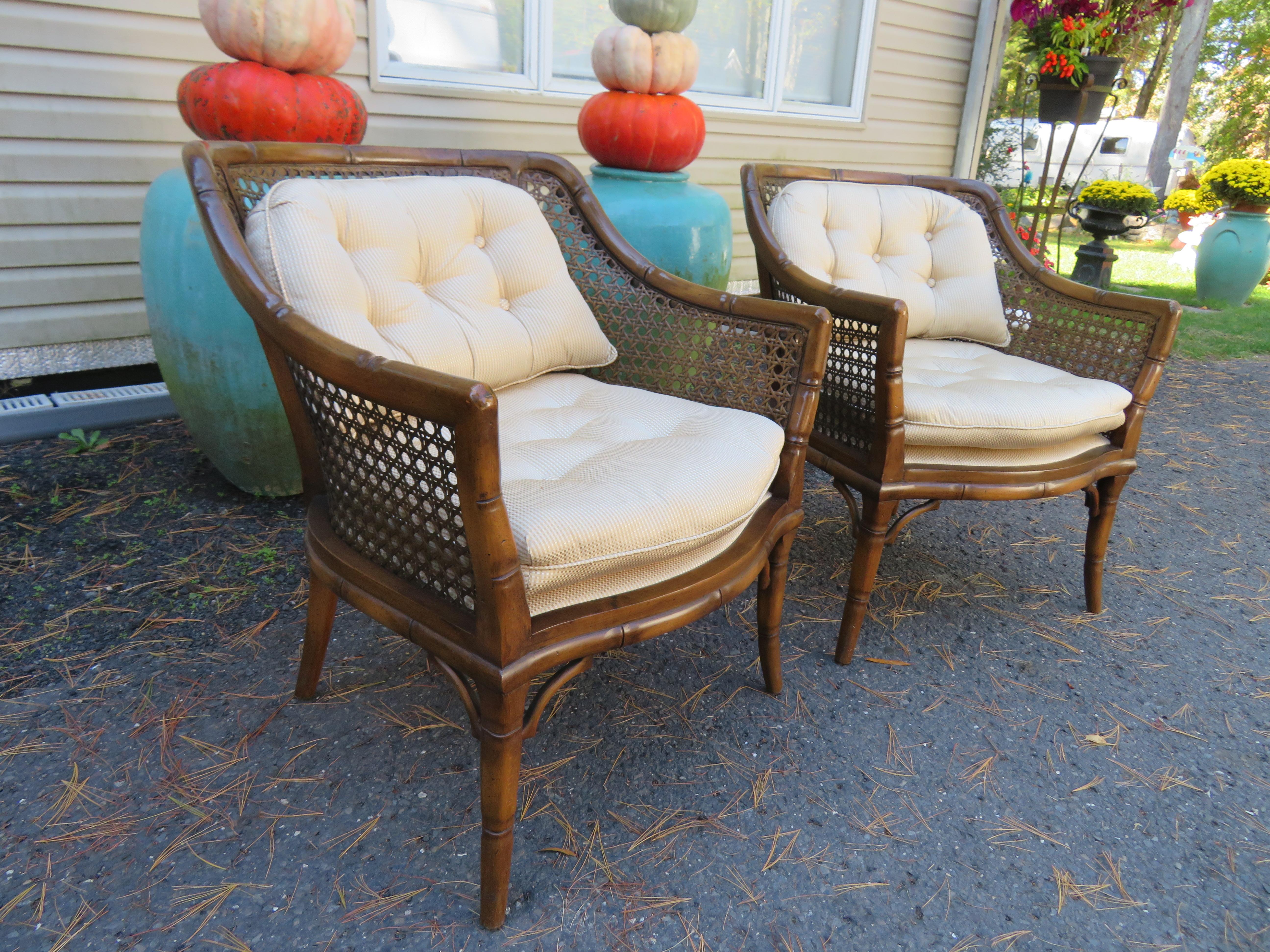 A wonderful pair of faux bamboo caned club chairs with a glossy light tortoise finish. The sturdy frames with caned back and sides with cushions in an ivory cream subtle pinstripe. These chairs measure 32