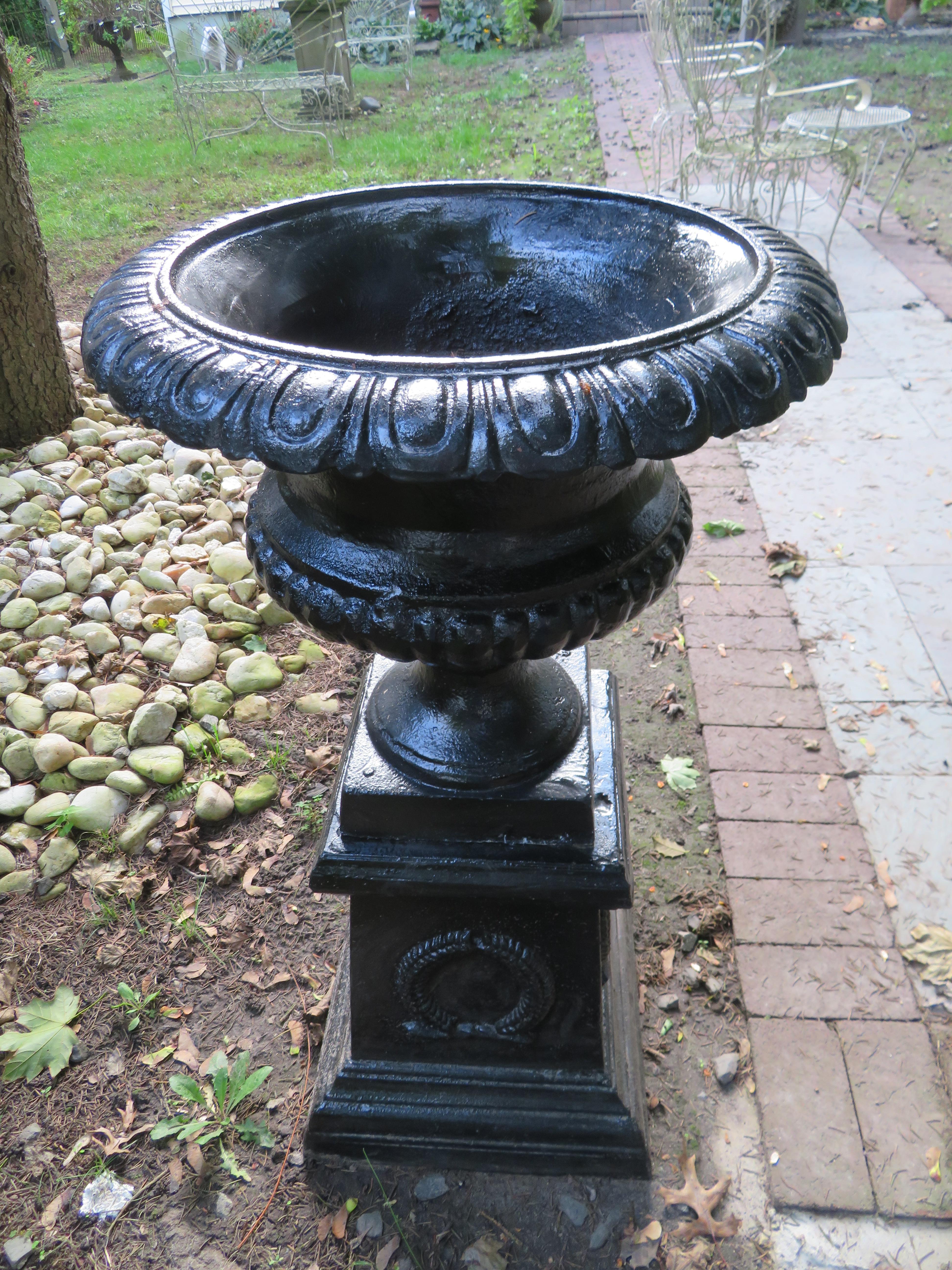 Handsome pair of 20th century cast iron urns on detachable pedestals. This pair has a new coat of black paint and look great-ready to be used and displayed in your garden.