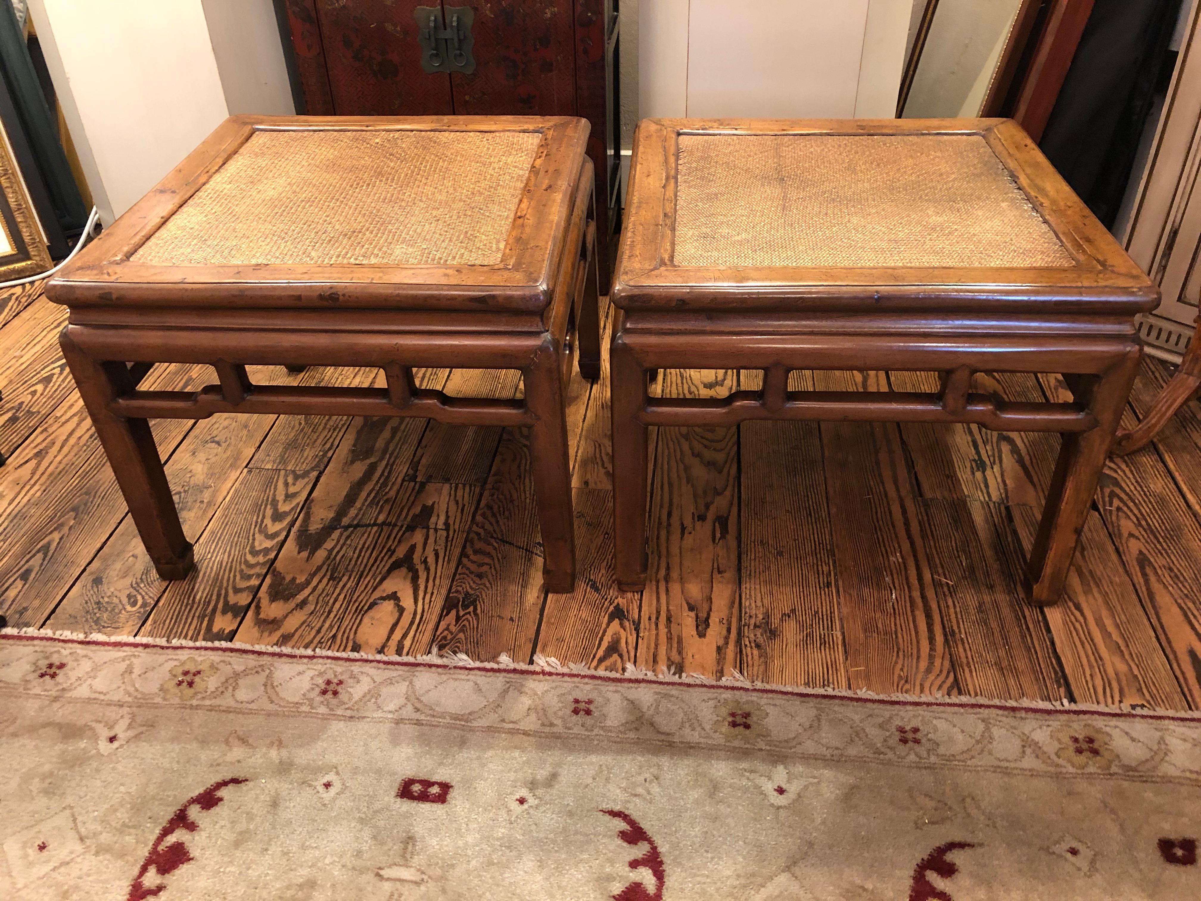 Handsome pair of 19th century honey colored elm square end tables using traditional mortise-and-tenon joinery techniques. The tables feature straight legs ending in hoofed feet and textural rattan tops. The clean lines of the frames are contrasted