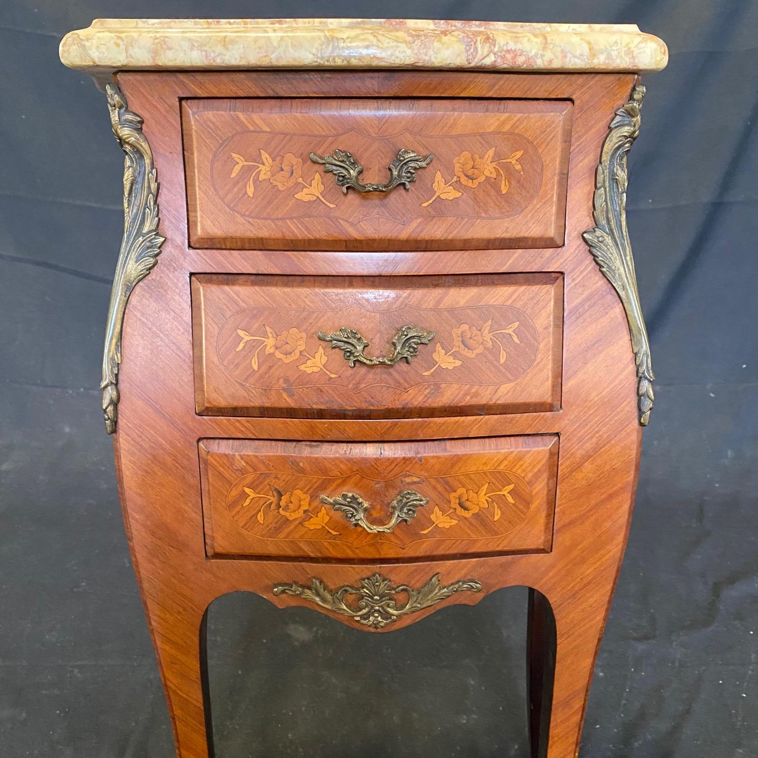 Pair of classic French Louis XVI walnut and marble top night stands having drawer casework with curved sides supported by four tapered and fluted legs. A single cast bronze pull accesses each of the three drawers and the tops are fitted with