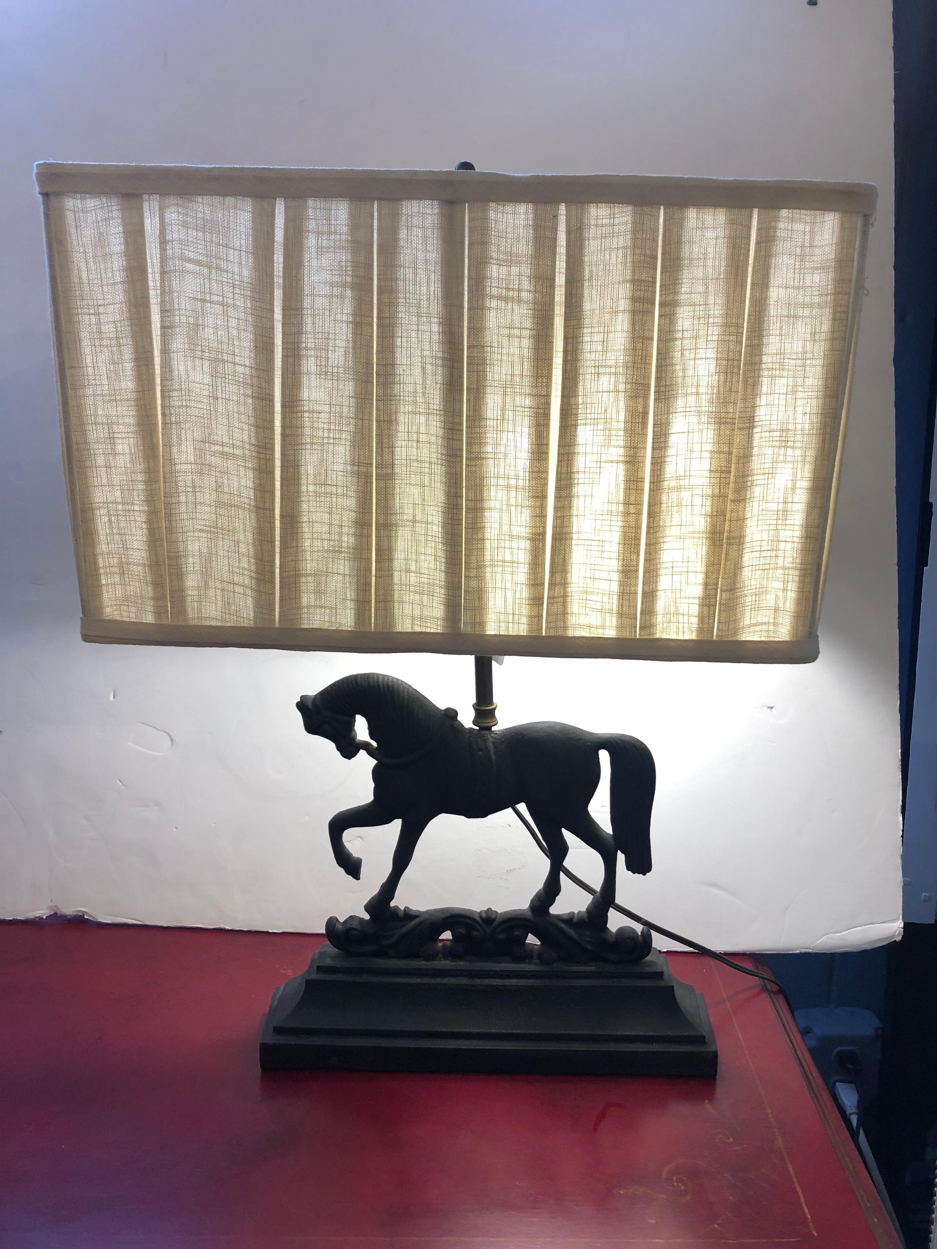 Handsome pair of black wrought iron table lamps having regal horse sculptures in opposing position, each with one leg elegantly lifted. Custom contemporary rectangular pleated shades are included.
The lamp itself is 13.5 W x 7 D.