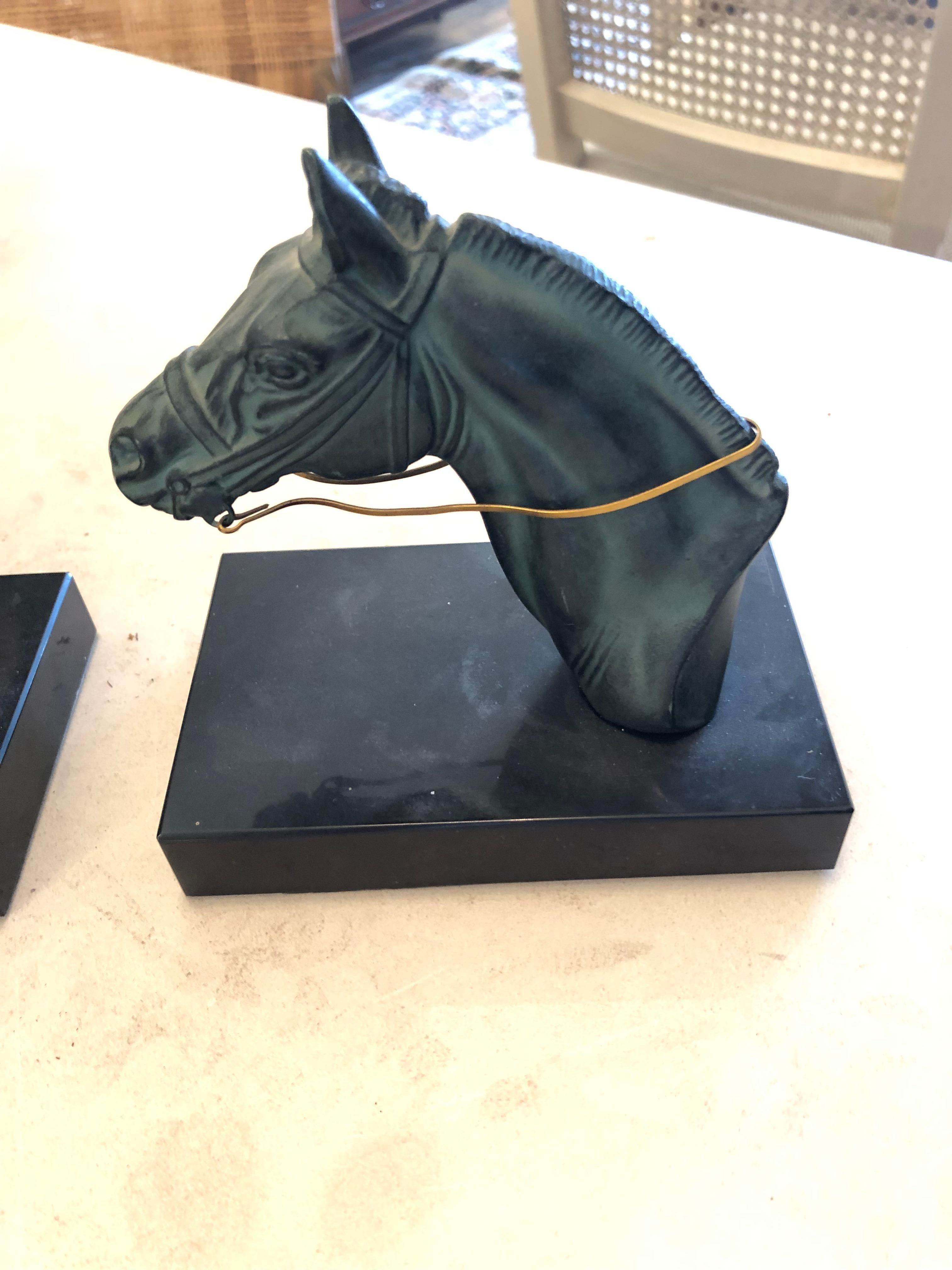 Bellissima coppia di fermalibri a testa di cavallo in metallo verdastro su basi nere con regni dorati.  Decorativo e funzionale.