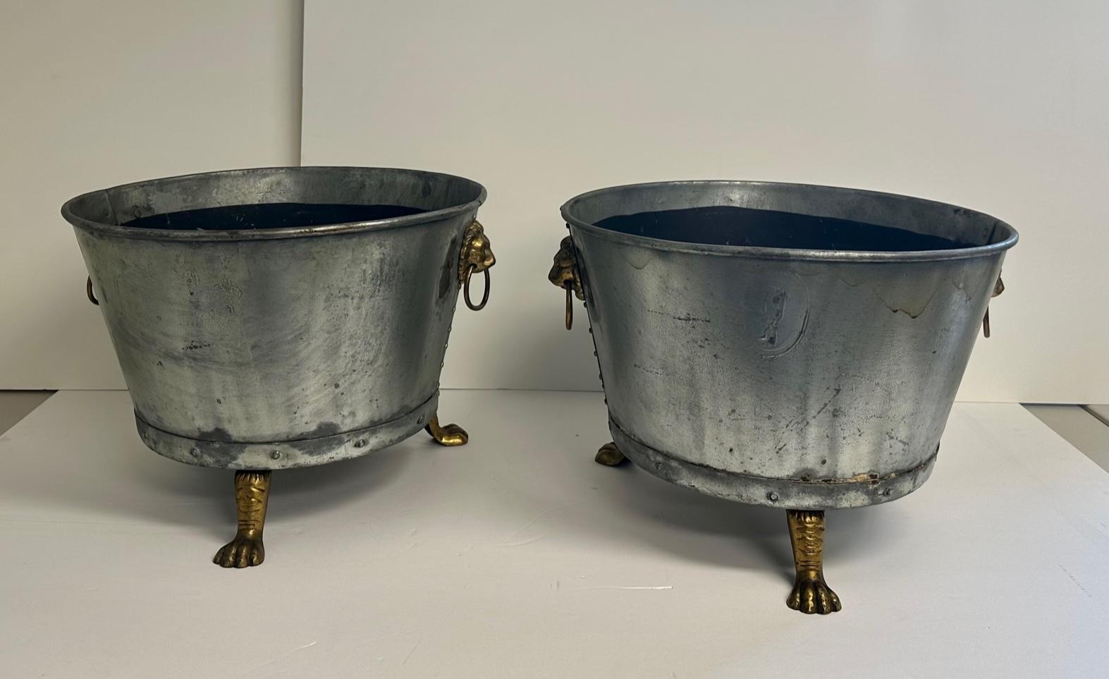 Handsome pair of galvanized metal round planters having fabulous neoclassical brass lion handles with rings and paw feet.
Inside is 12