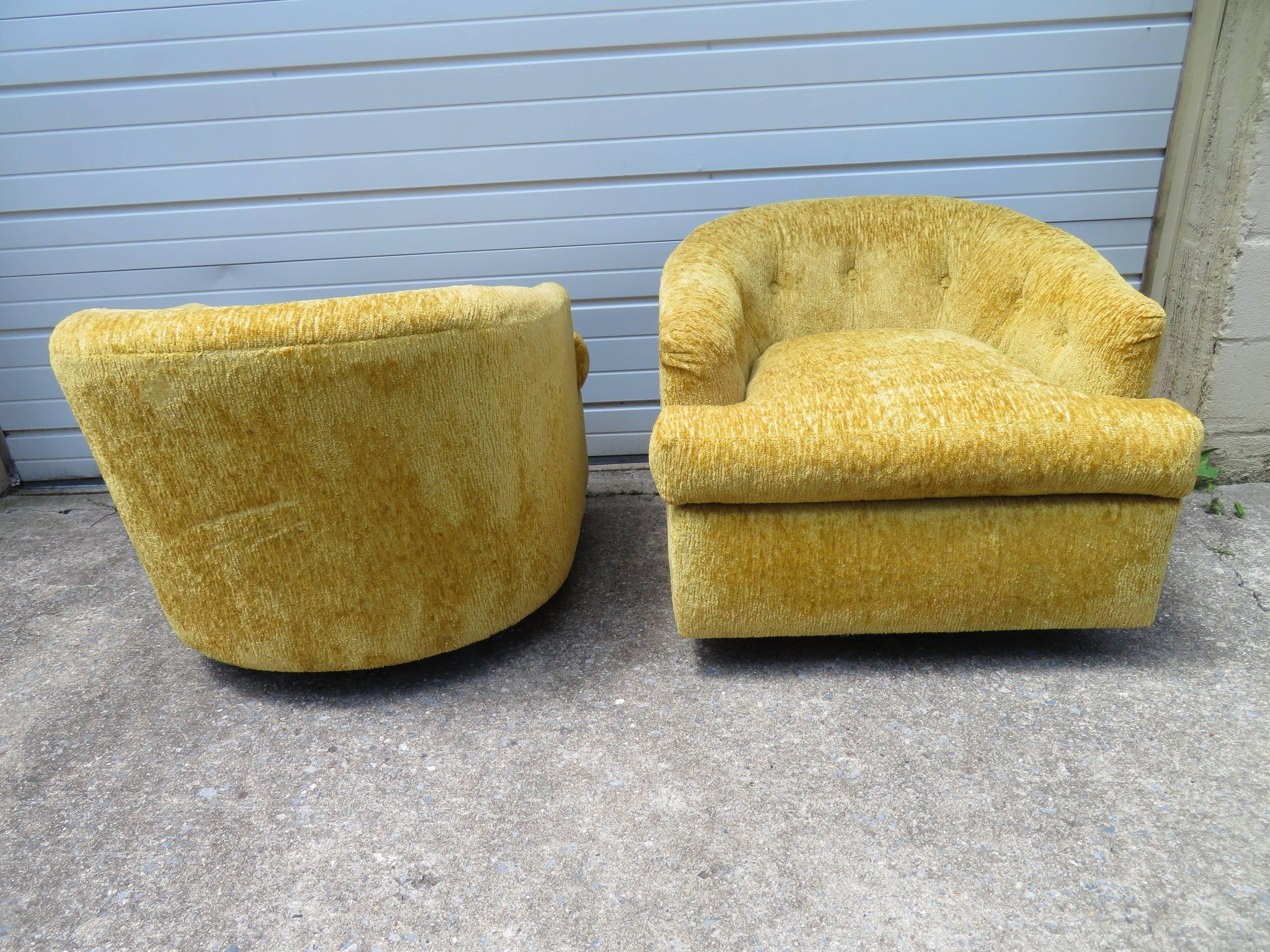 Handsome pair of labeled John Stuart swivel barrel back lounge chairs. These chair provide exceptional comfort along with smart vintage style. We love the rollers on the bottom enabling the chairs to scoot anywhere you want to go. Upholstered in
