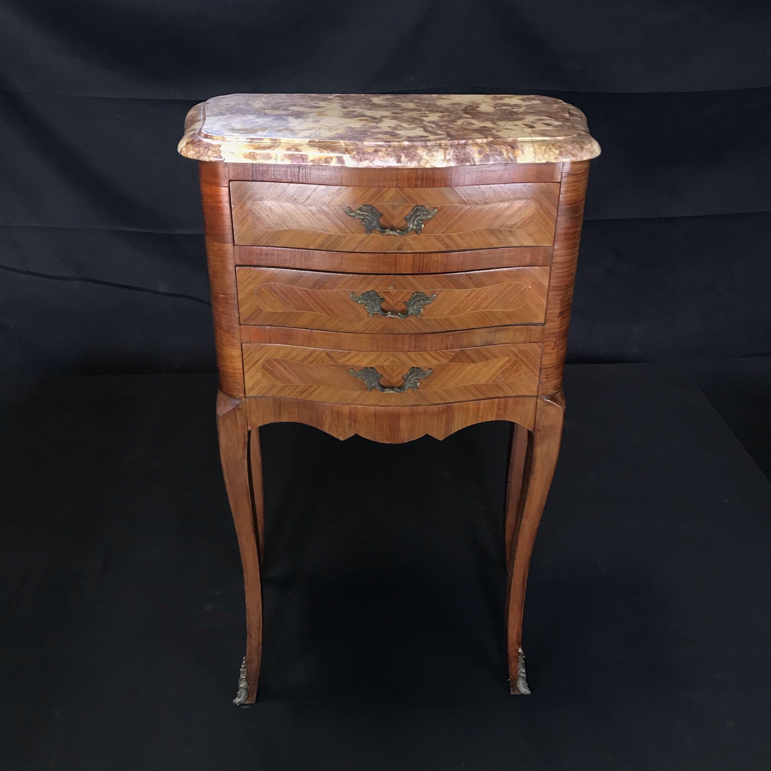 These elegant three-drawer bedside tables were created in France, circa 1900. The petite chests stand on cabriole legs ending with bronze sabot feet decorated with acanthus leaves under a scalloped apron; both sides with serpentine shape have