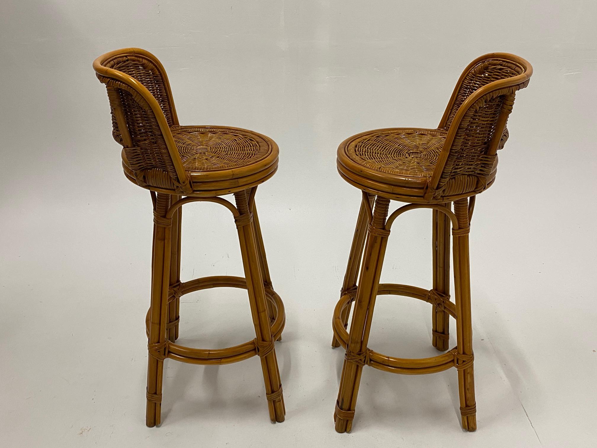 A cool woven rattan pair of Mid-Century Modern barstools having comfy curved backs and ring shaped foot rests.