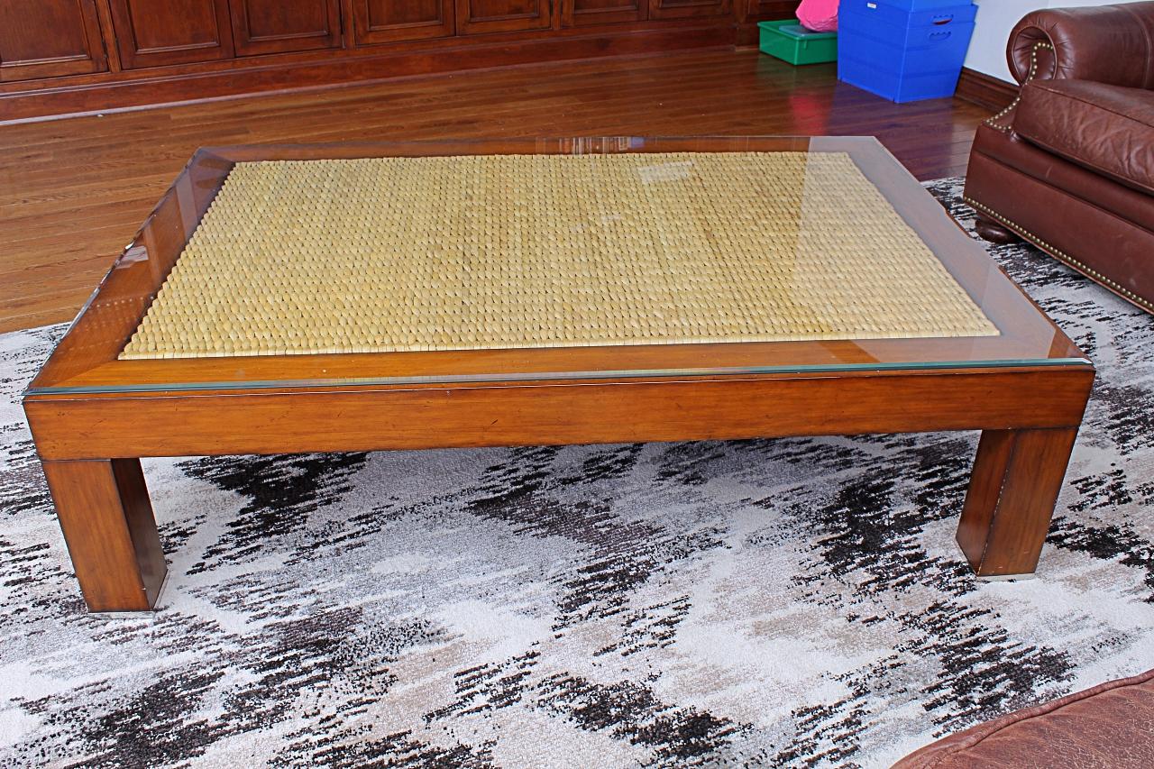 A Ralph Lauren stylish rectangular coffee table having simple modern lines and a combination of inset natural color seagrass top, wooden base, and removable glass surface.