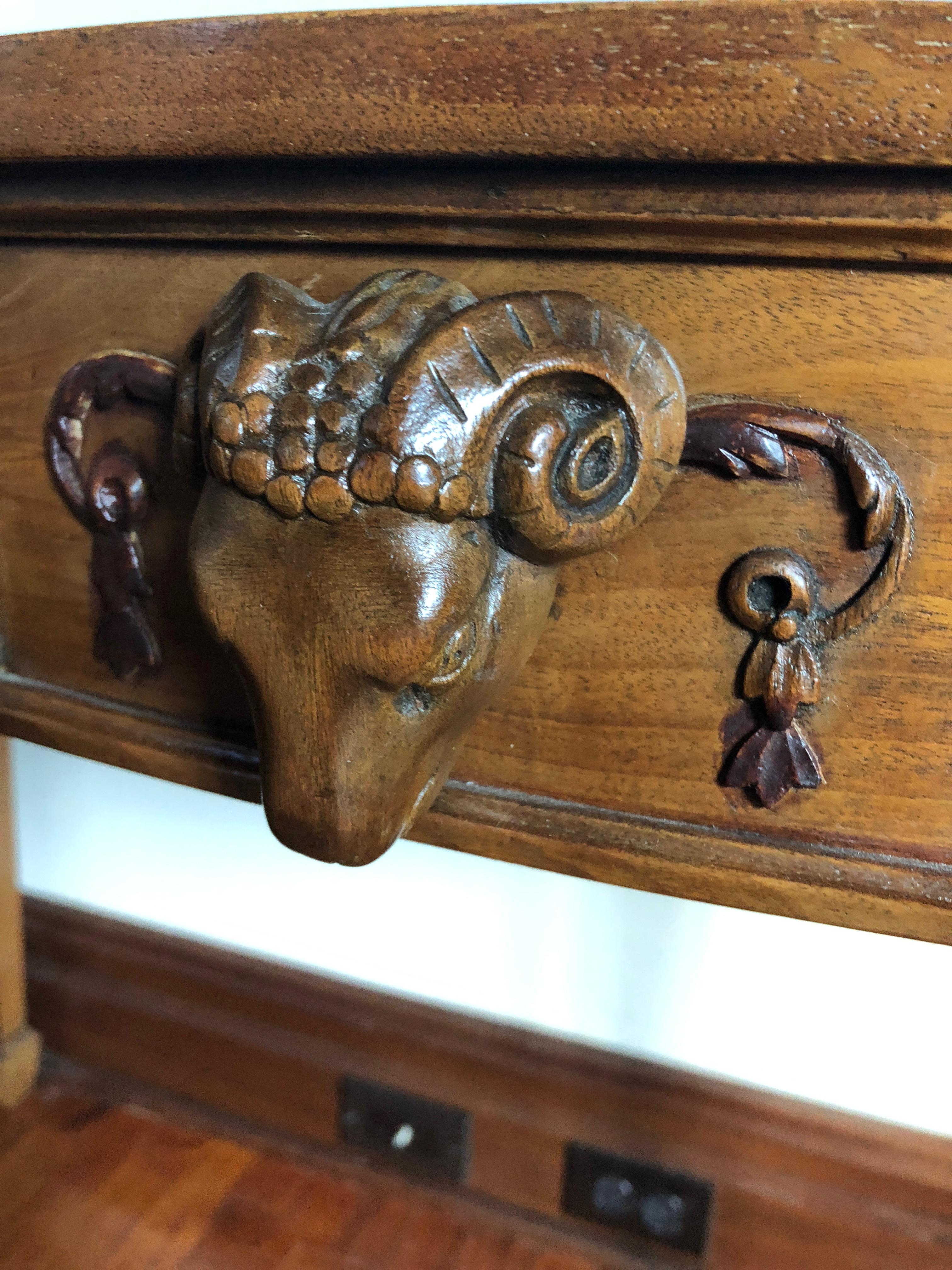 Stunning demilune console in a honey colored wood having carved ram's head on the center front and decorative swirls on the apron as well as carvings on the elegant tapered legs.

 