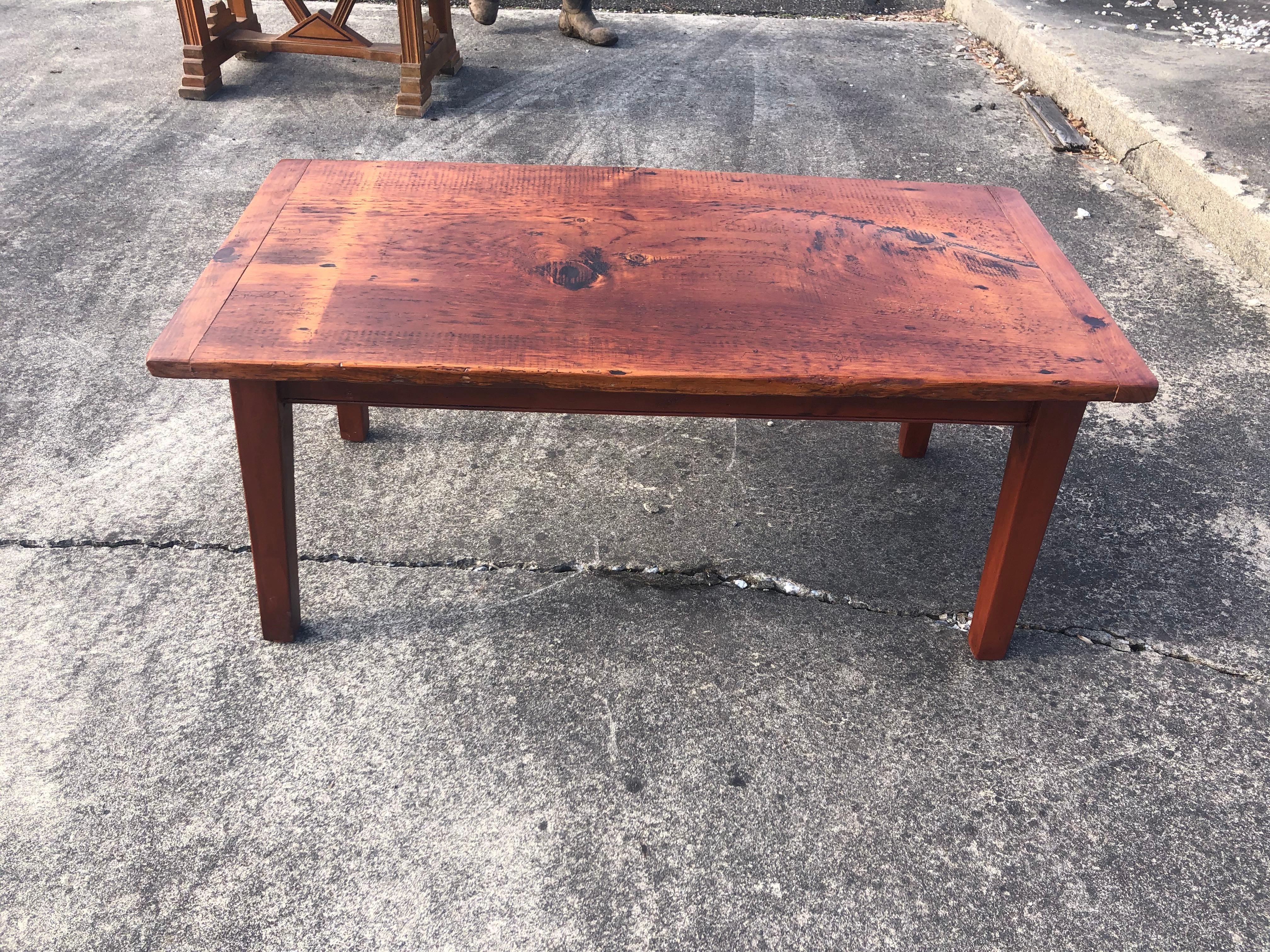 Handcrafted pine plank coffee table by Maine artisan. Legs are simple tapered design and top has beautiful rustic character. The table appears to have a slight ripple, natural to the barnwood that was salvaged.