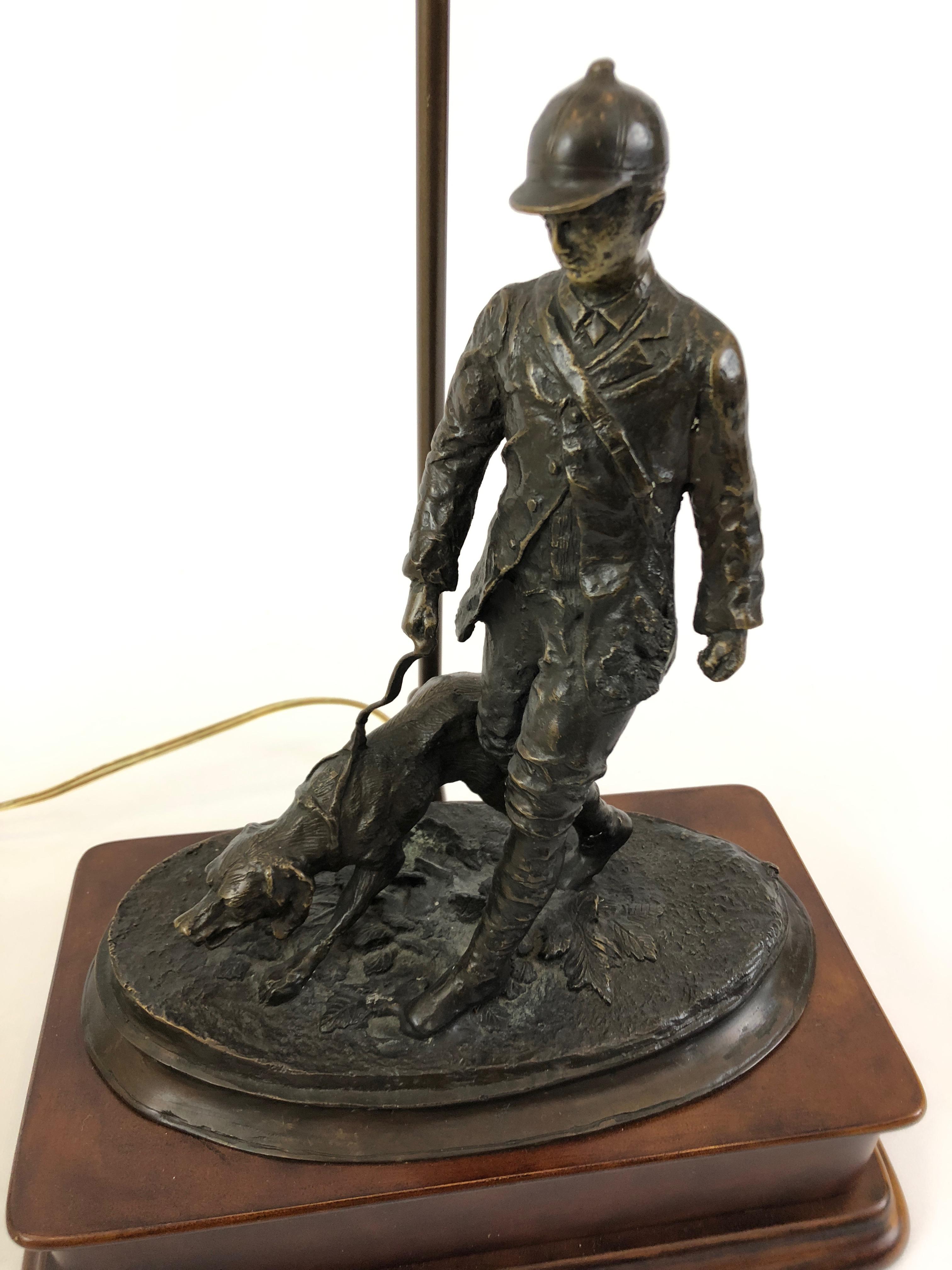Kunstvolle Tischlampe mit Bronzeskulptur eines Jägers und seines Hundes auf Holzsockel mit schönem Seidenschirm und dekorativem Abschluss. 
Die Skulptur ist 15::5 H
Die Basis ist 12::25 x 6::75.
