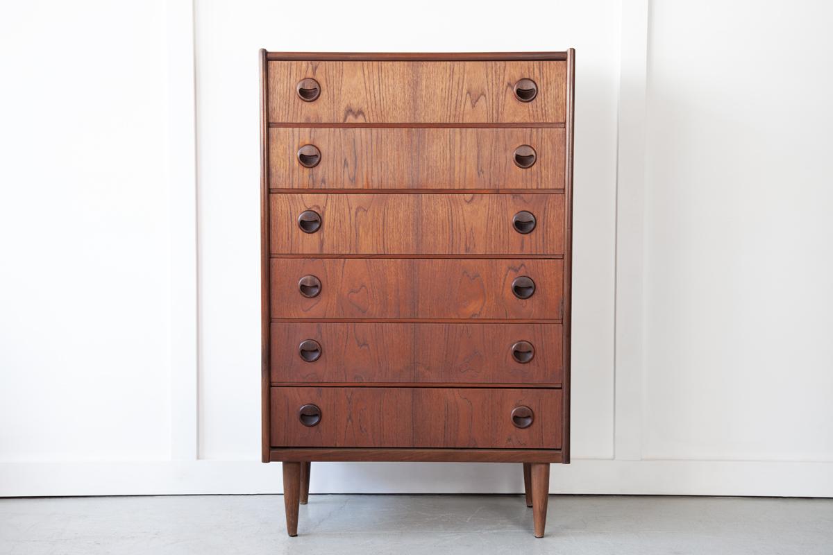 A very handsome Danish teak tallboy with 6 spacious drawers which display some beautiful grain detailing. This chest has the iconic 'smile' inset handles designed by Kai Kristiansen. 