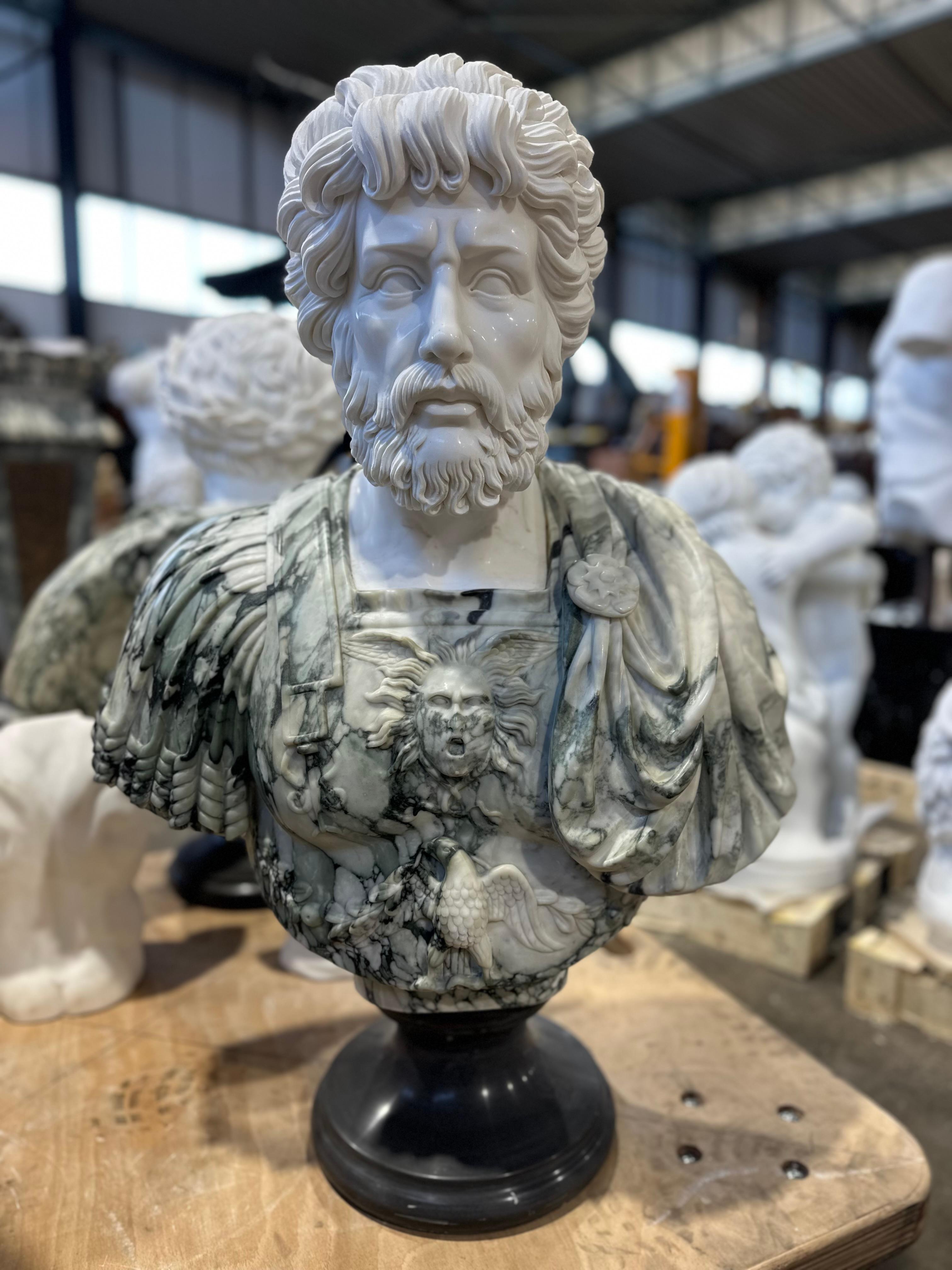 A handsome green and white marble male bust, on a black marble stand. A intricately detailed and imposing male marble bust with elaborate carvings to the breastplate showing a eagle and winged miniature face possibly Ares God of War. The males