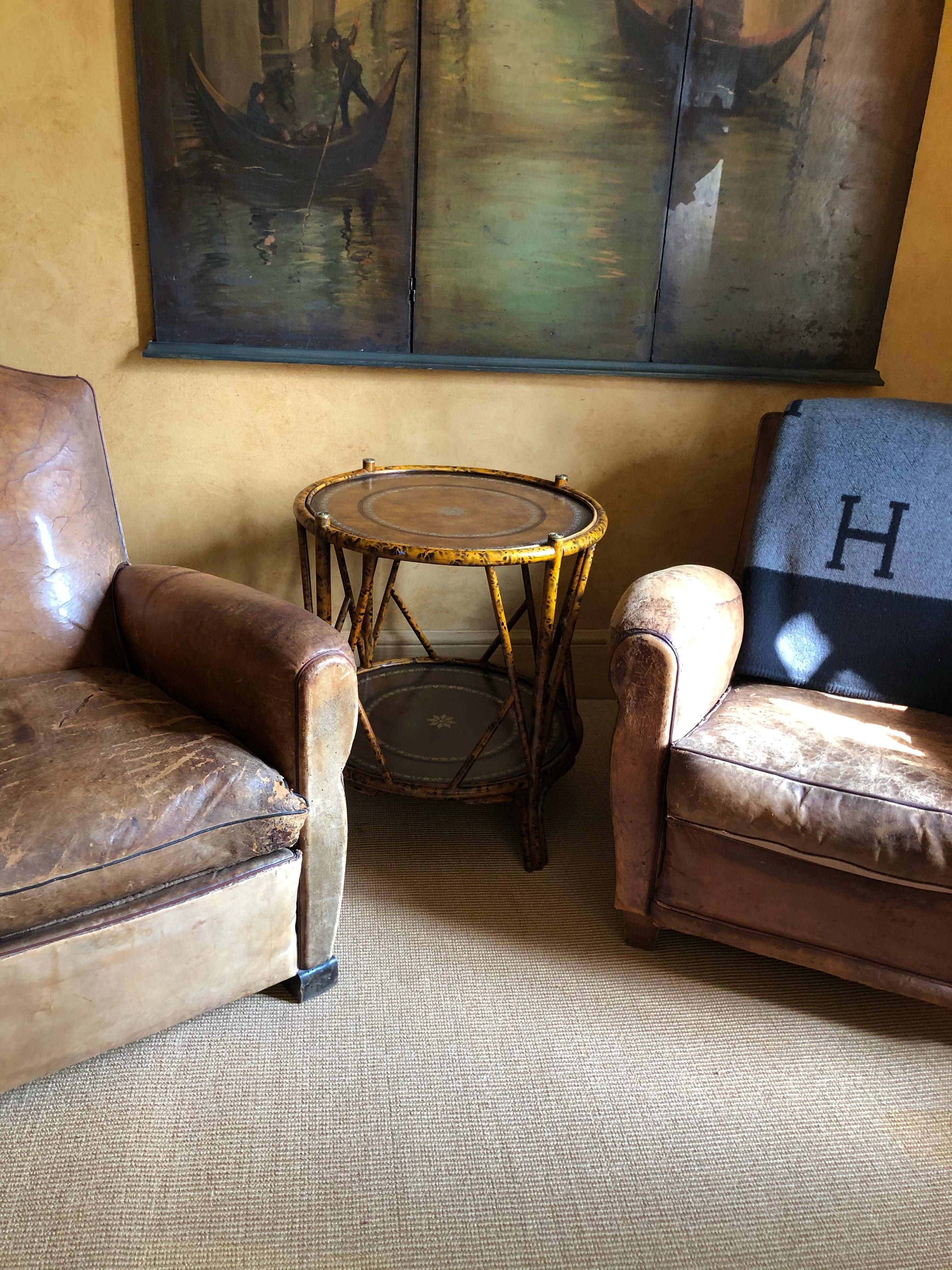 A unique vintage bamboo and leather side end table having two leather surfaces both tooled in gold. It is decorated with brass caps on the top and brass caps on the feet. The bamboo has great color and patina and the size of the table is perfect