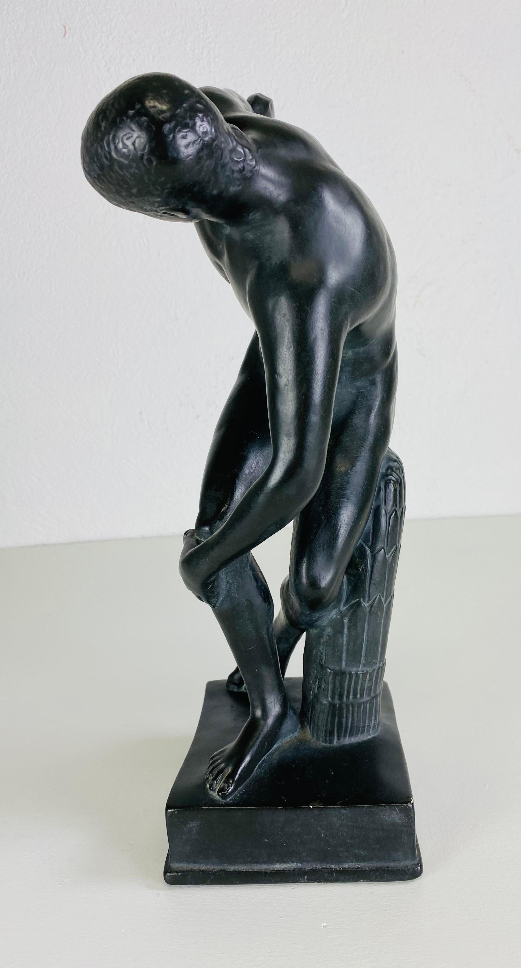Se trata de una escultura figurativa grecorromana de estilo clásico de mediados de siglo. Esta escultura tiene un acabado de bronce oscuro patinado en la superficie. Esta escultura de estilo grecorromano representa a un atleta masculino lanzador de