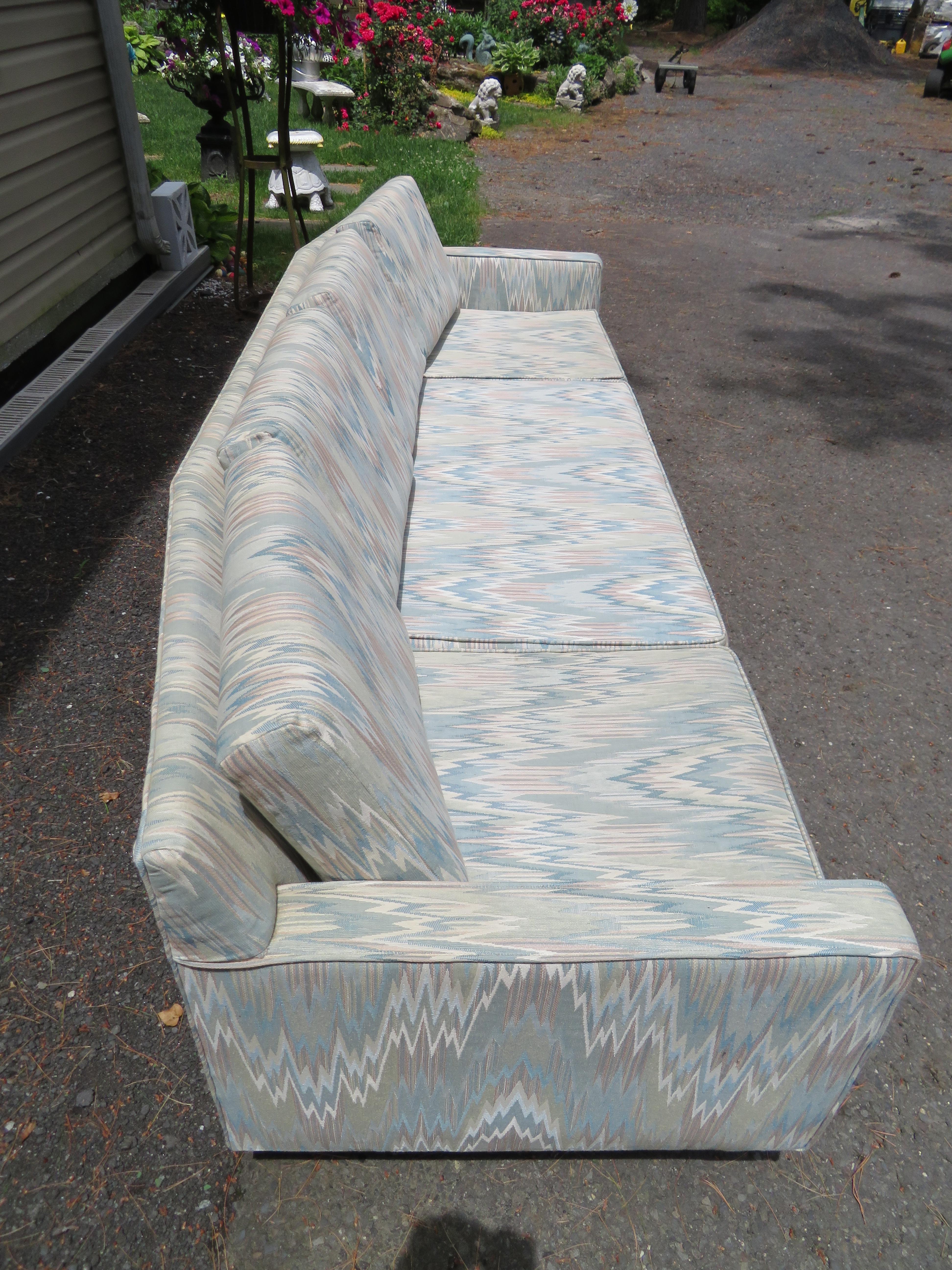 Handsome Edward Wormley style 4 seater curved sofa. We actually love the original light blue zig-zag fabric still in clean usable condition. It measures 29
