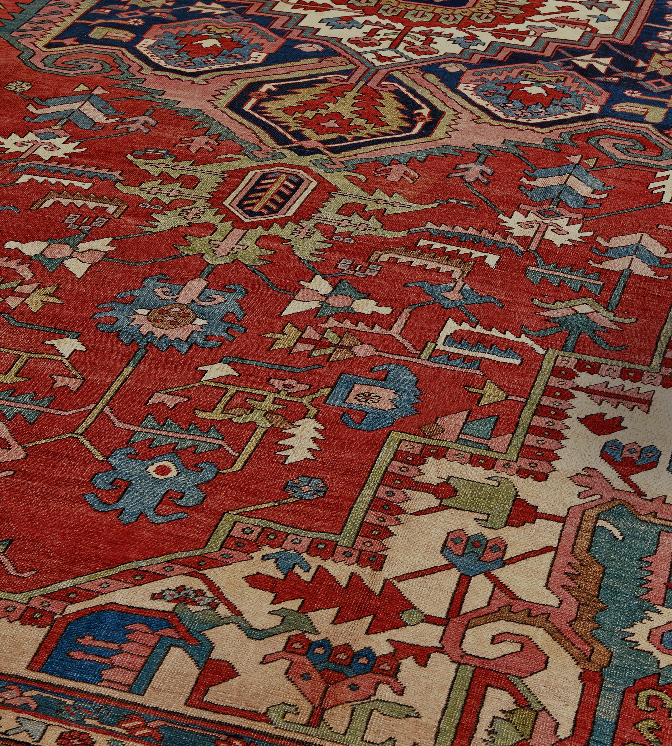 Dieser antike, um 1880 entstandene persische Serapi-Teppich hat ein ziegelrotes Feld mit einer polychromen eckigen Palmette und einer gezackten Blattranke um ein indigoblaues und staubrosa Zentralmedaillon und moosgrüne Palmettenanhänger, die