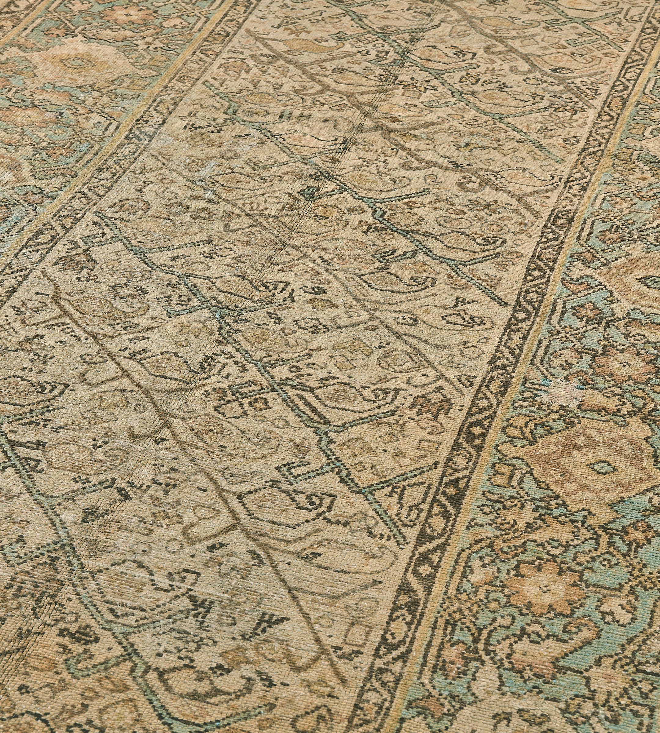 Questo antico tappeto persiano Malayer del 1900 circa presenta un campo avorio con un motivo generale di file diagonali di viti angolari blu chiaro e marrone talpa che emettono boteh e teste di fiori insieme ad altri motivi floreali, in un bordo blu
