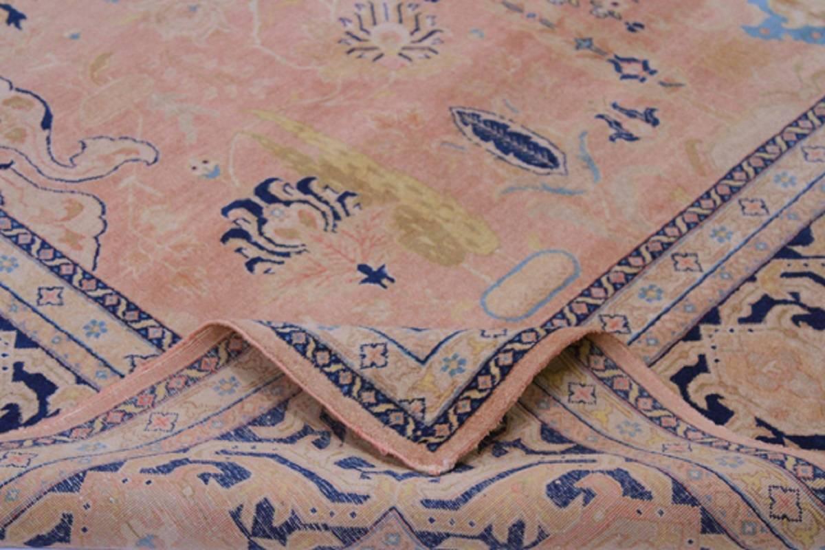 Handwoven antique Persian Tabriz rug with a stylized flower and geometric motif on a shrimp colored field and blue border accented in shades of ivory, brown, amber, teal and sand.  Created from 100% wool by the artisans of Iran, circa 1920.