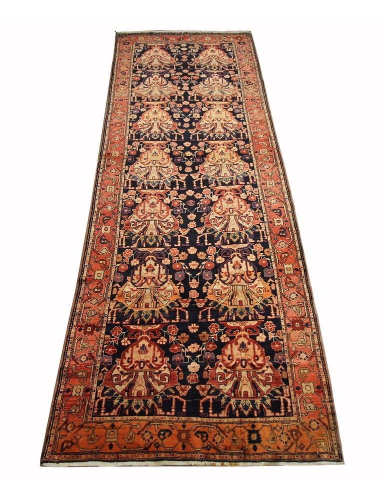 This elegantly woven carpet was constructed in Azerbaijan in the 1930s. It features several vases of flowers and a bold colour palette, including rust, cream, purple and deep blue. The design features 14 elegantly woven vase floral designs. A