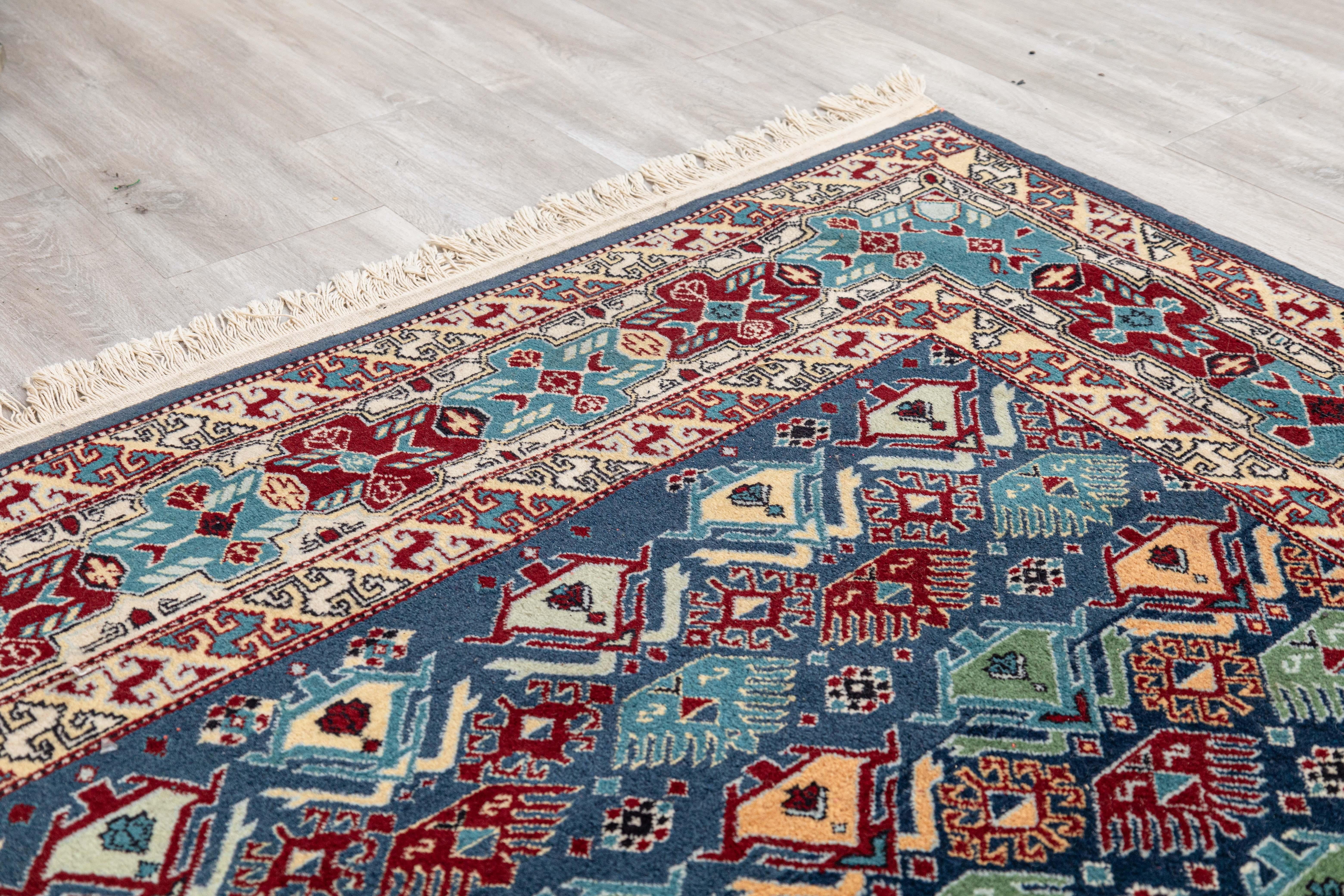 A handwoven Azerbaijani area rug. This beautifully crafted area rug features a handwoven patterning featuring a multicolor design. The rug has lovely blues, greens, reds, and yellows sewn throughout it. The many different patterns and shapes create