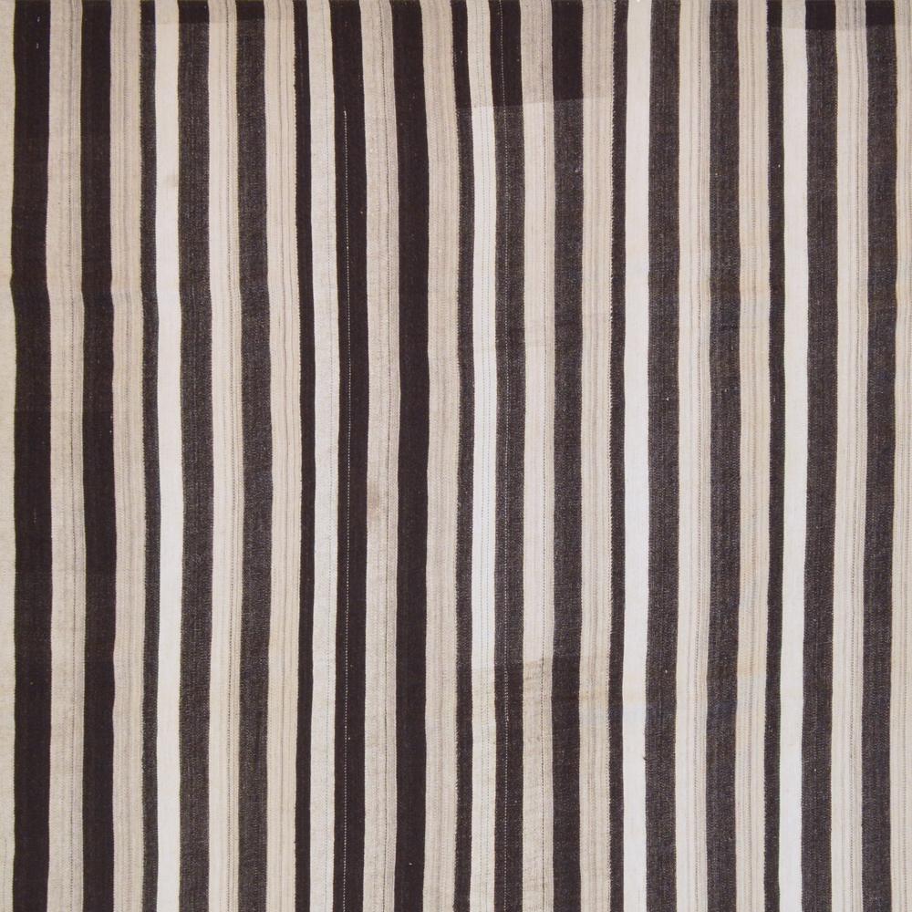 This vintage Kilim was handwoven in the second half of the 20th century. The flat-woven rug is woven from uncolored natural wool in the colors dark brown to black and creamy
white.