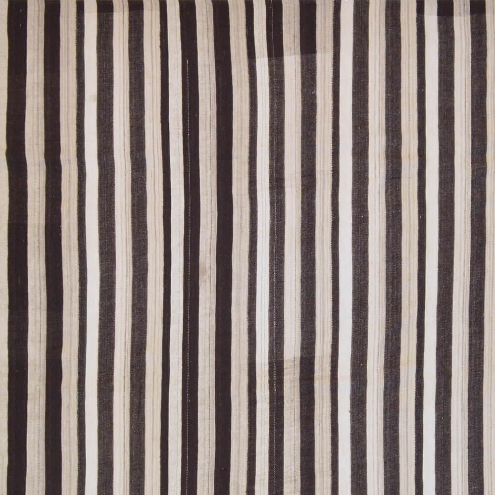 Dieser Vintage-Kilim wurde in der zweiten Hälfte des 20. Jahrhunderts handgewebt. Der flachgewebte Teppich ist aus ungefärbter Naturwolle in den Farben Dunkelbraun bis Schwarz und Cremeweiß gewebt.