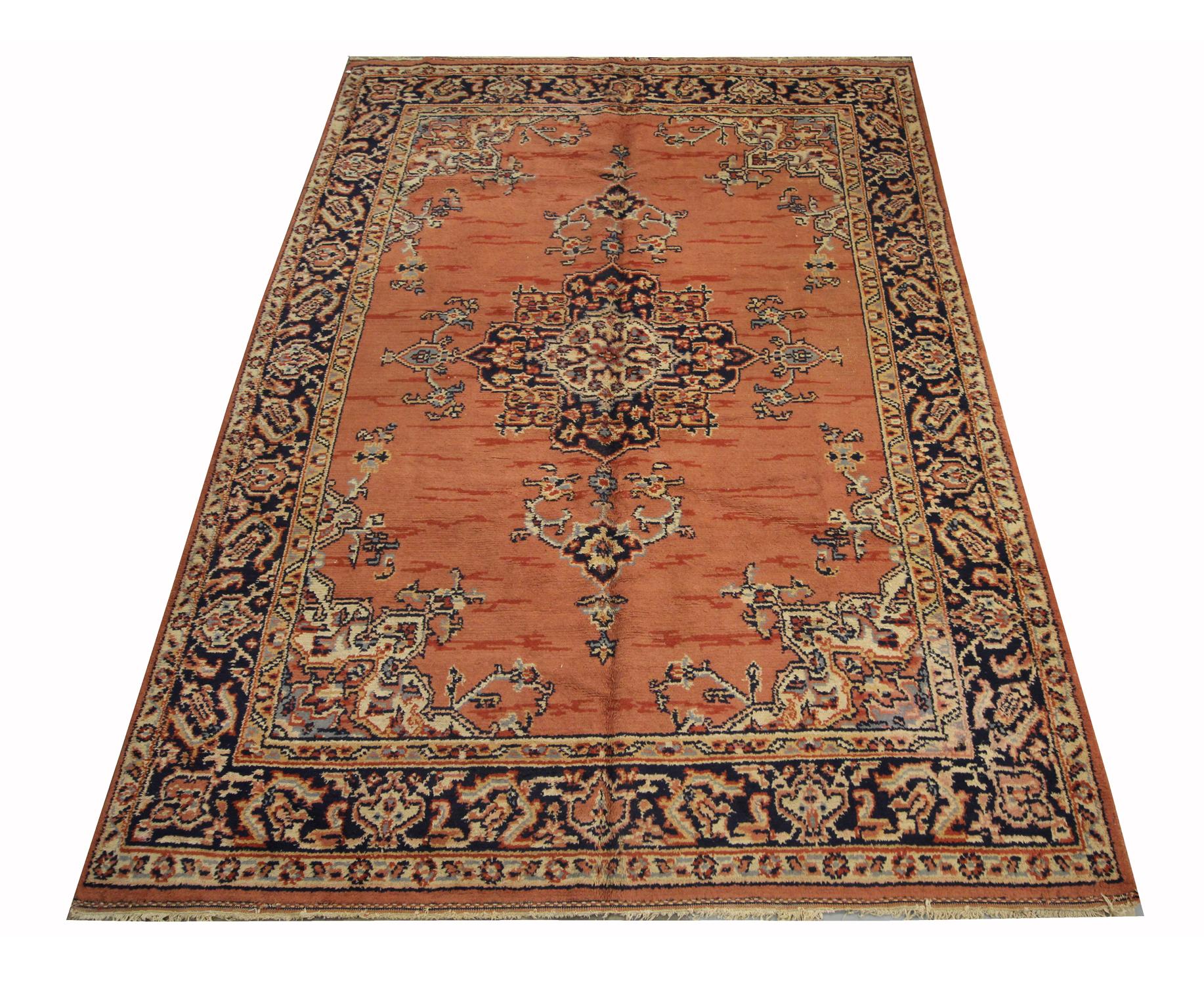 This fine wool is an Indian wool rug that was woven by hand in the 1930s. It features a traditional medallion design with a rich orange background that has been decorated with a delicate medallion and symmetrical surrounding design and border.