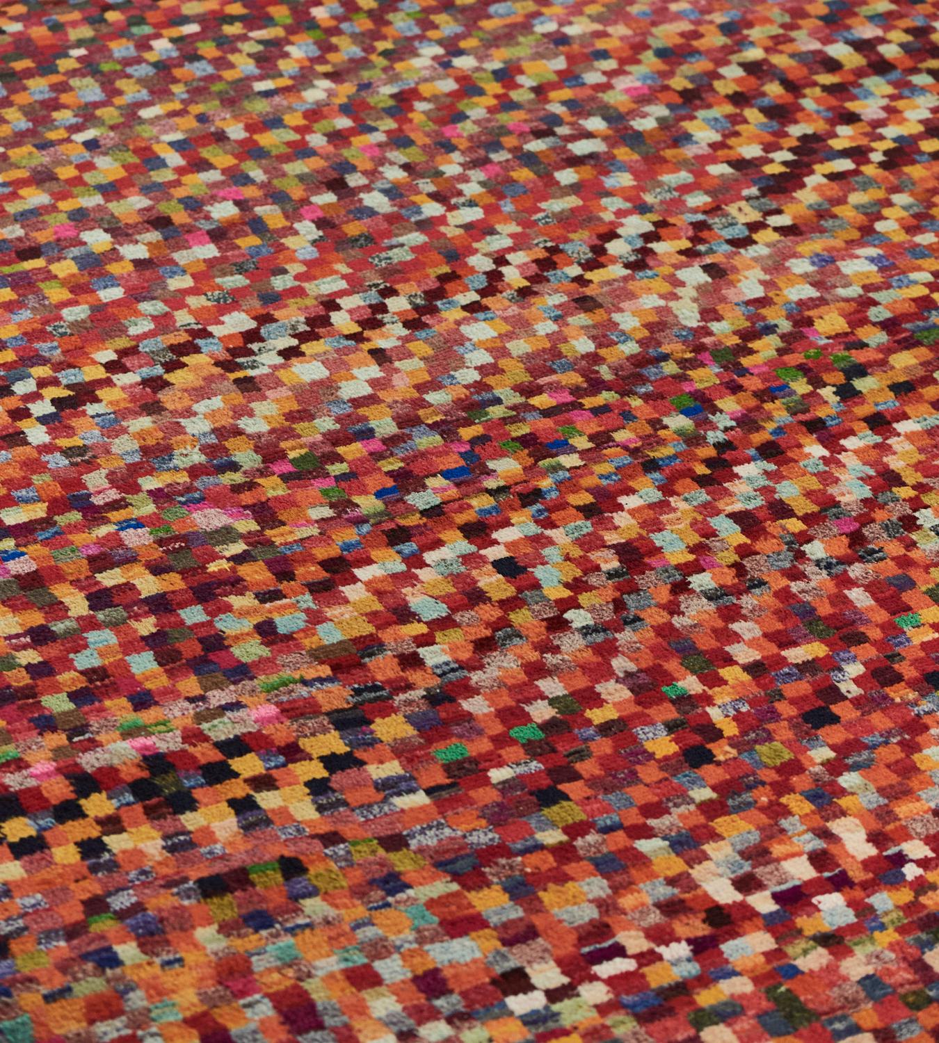 Faisant partie de la collection Mansour Modern, ce tapis déco à poils profonds, tissé à la main, présente un champ global de cellules polychromes dans une bordure rayée rouille et rouge.