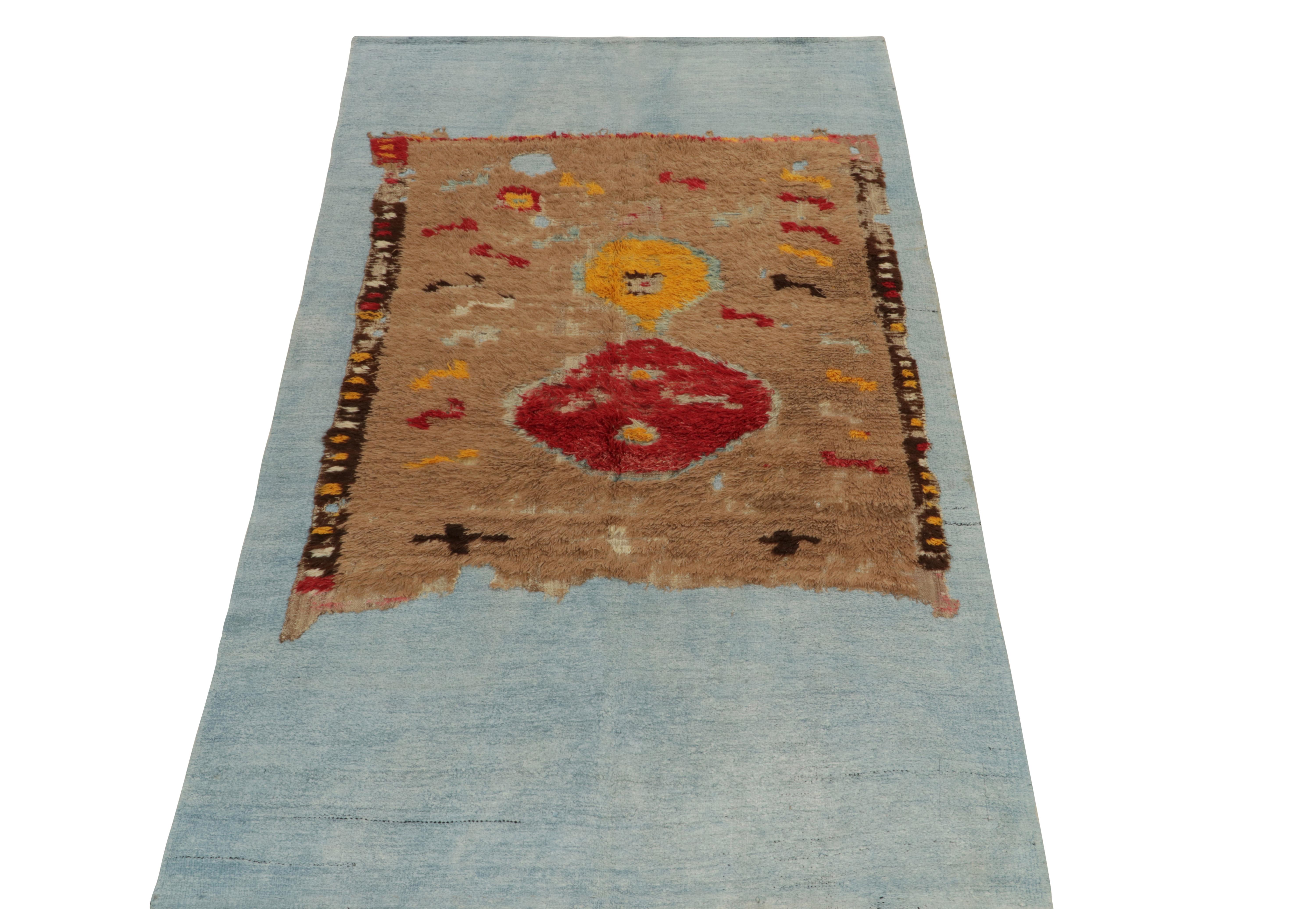 Hand-knotted in fine wool,a 5x10 fragment rug bearing distressed aesthetics resting calmly on a blue-gray flatweave. The fragment prevails in bright yellow, beige & red complementing a natural high low atop the flatweave—capable of adorning a