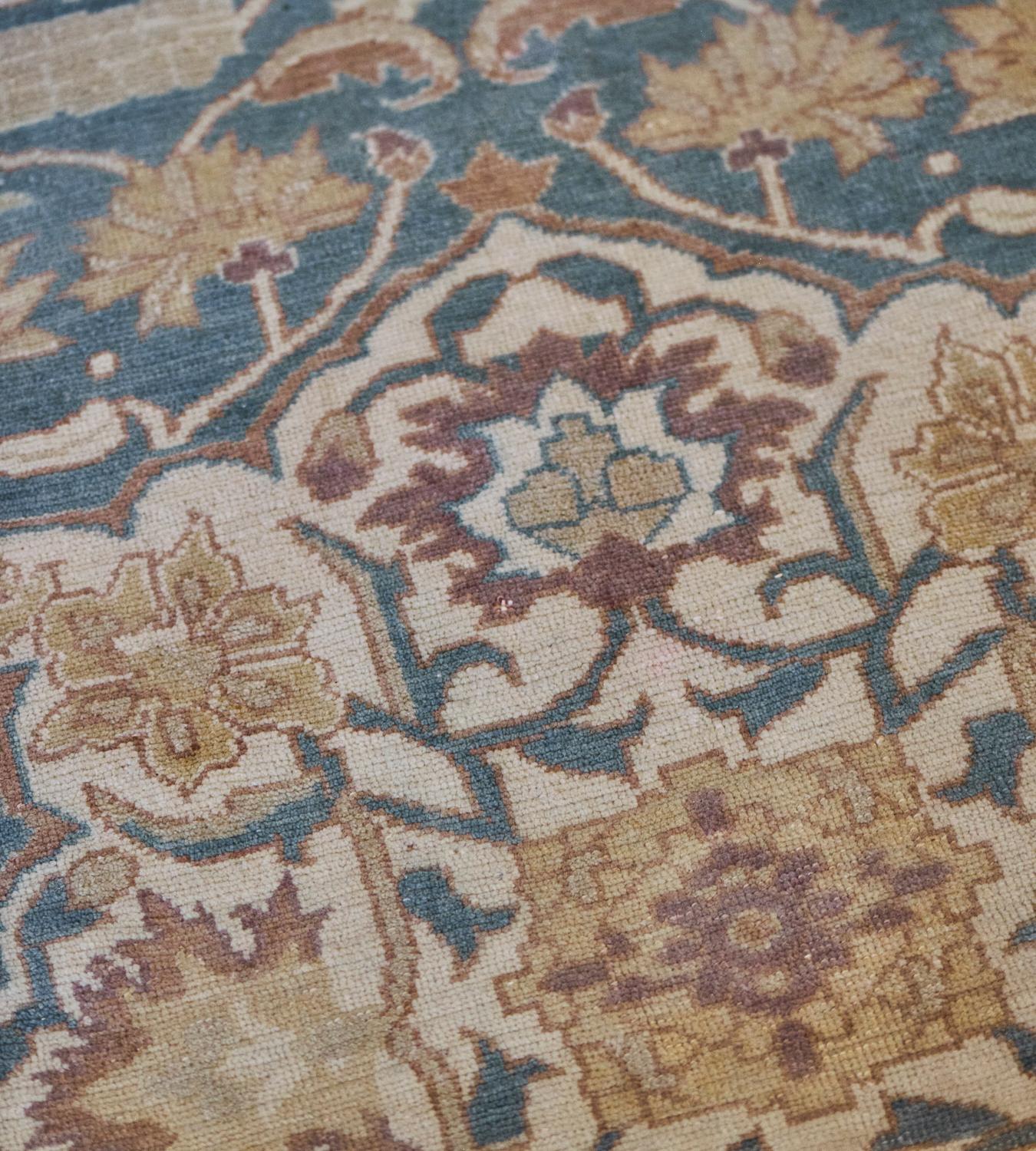 This antique handwoven Amritsar rug features a shaded sea-blue field with a dense ivory, fox-brown and buff-brown floral and palmette vine around a central ivory cusped medallion containing a central flowerhead issuing angular vine with a palmettes,