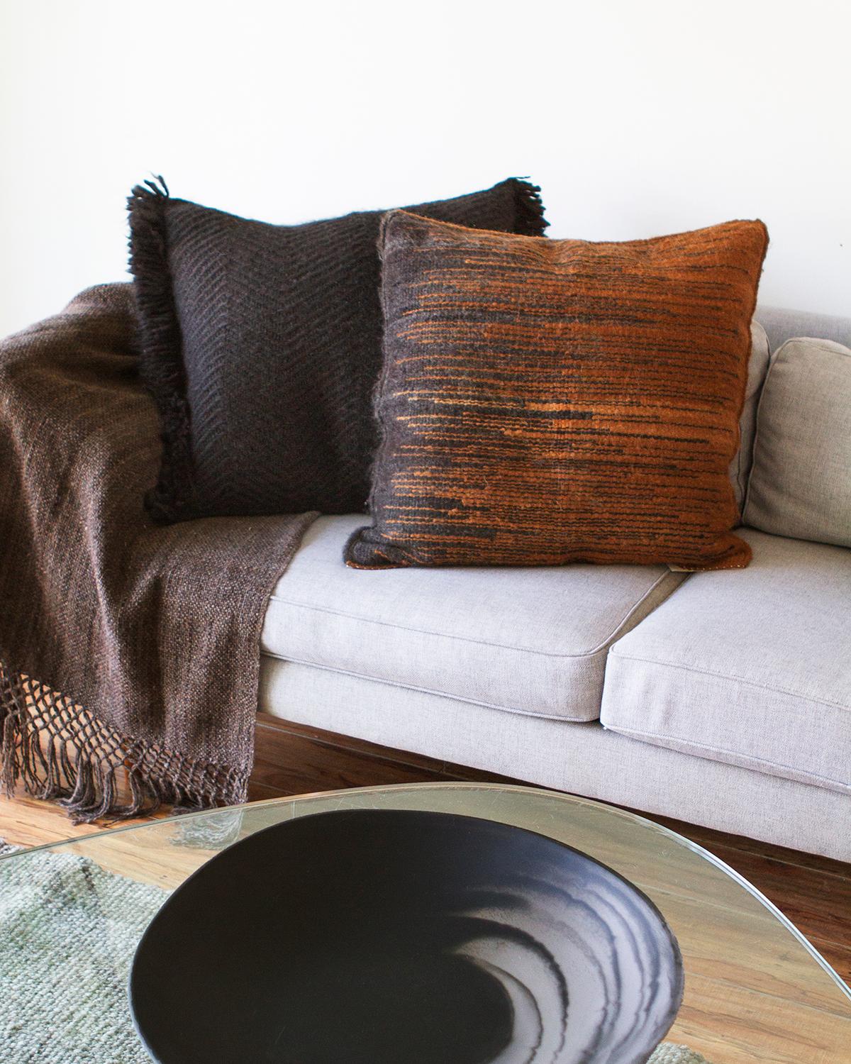 A warm cushion for your living room
This artisanal pillow is crafted from luxurious llama wool and features a unique chocolate brown and black geometric-striped design. Its large size makes it perfect for cozy lounging on a big couch in your living
