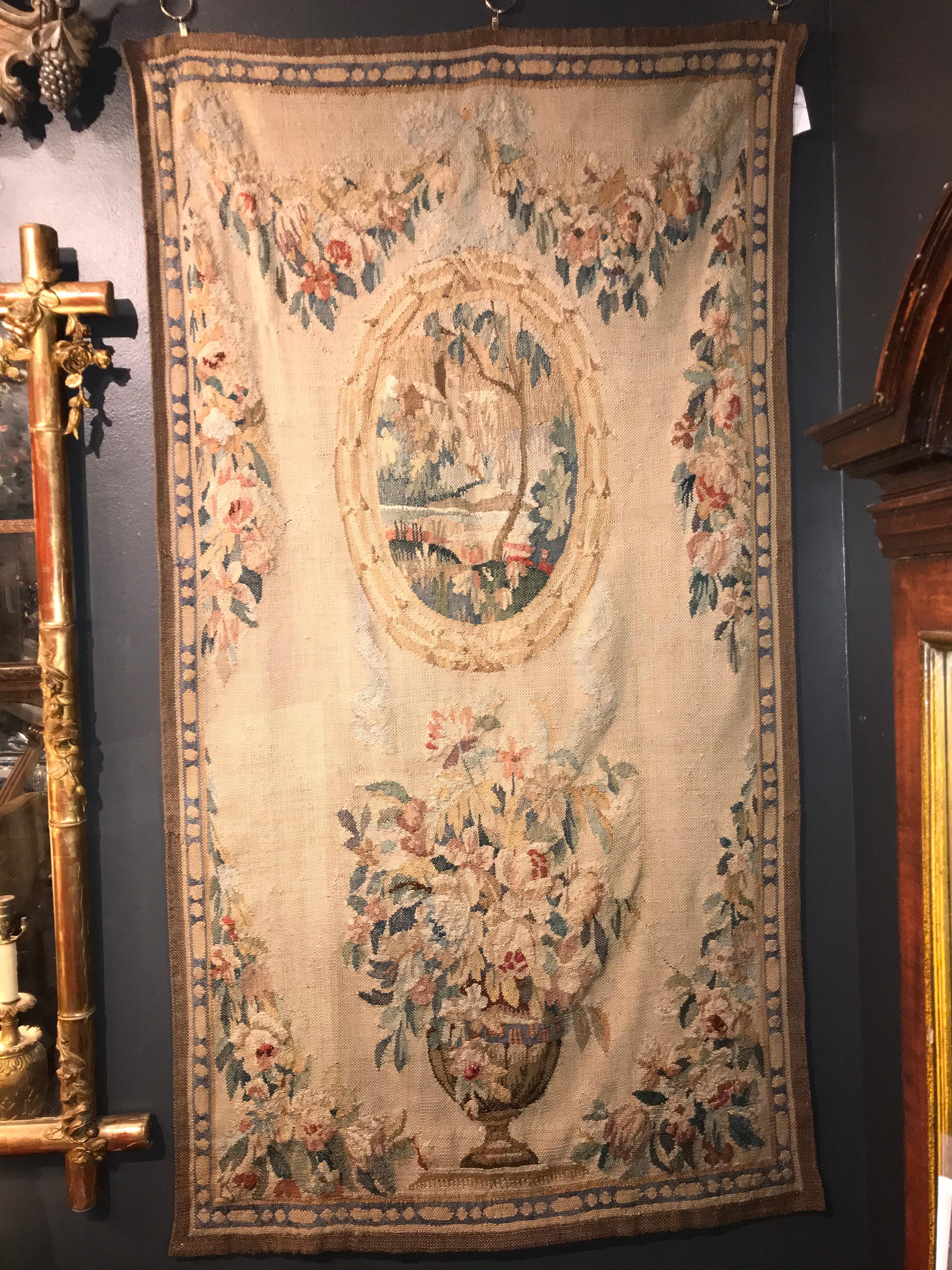 Floral decorated tapestry. Neutral background with floral bouquets and garlands centered around an oval lake scene. The lower panel decorated by urn with flowers. 

Strong Continental feel but unsigned 

Good condition, no sags or separations.