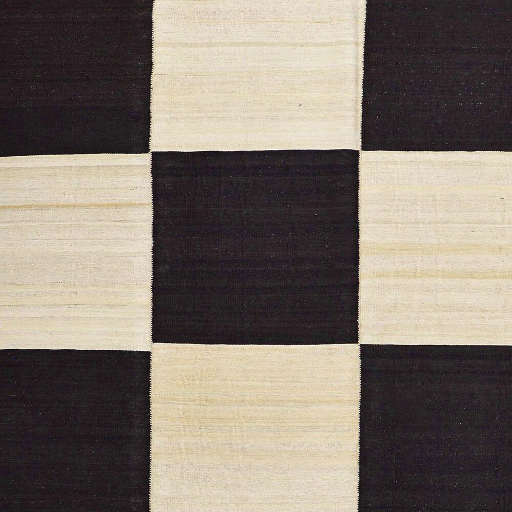 Questo caratteristico tappeto Mazandaran Kilim, proveniente dalla Persia settentrionale, presenta un audace disegno a scacchiera in bianco e nero che lo rende un'aggiunta straordinaria a qualsiasi arredamento. Il contrasto tra il nero profondo e il