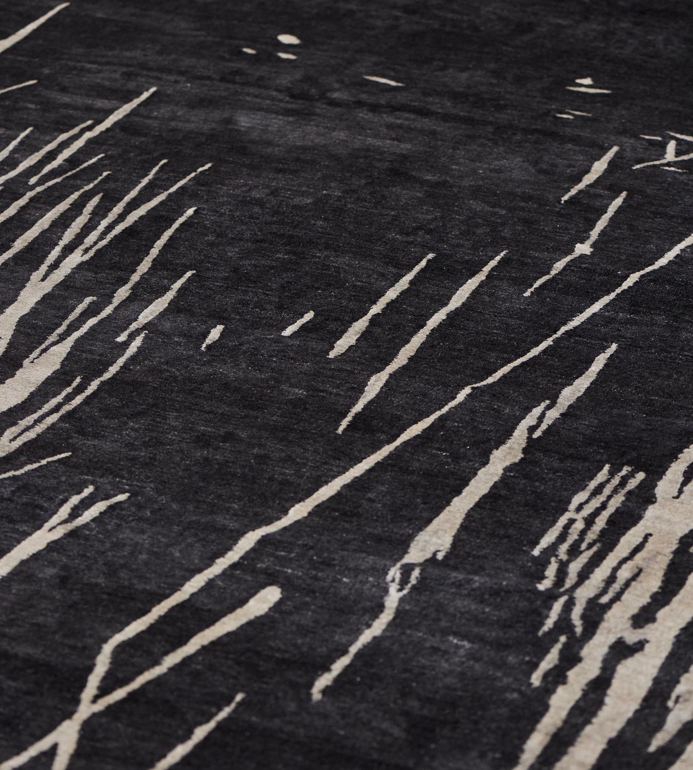 Faisant partie de la collection Mansour Modern, ce tapis contemporain en laine et soie présente un champ anthracite avec un délicat motif d'herbes longues stylisées en ivoire au centre.
