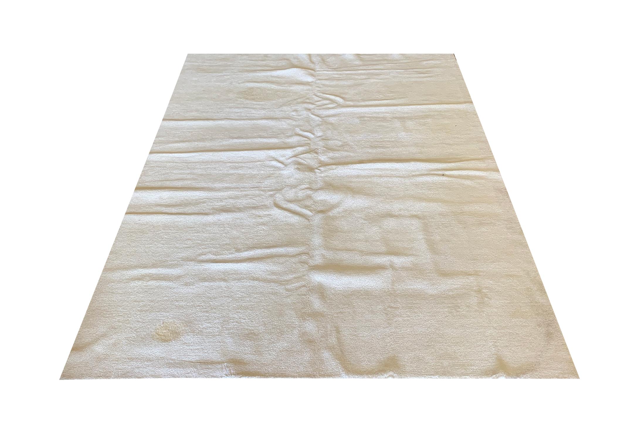 This sleek cream wool pile carpet is a minimalist piece woven by hand in India in the early 20th century, circa 1900. This subtle block colour area rug is simple yet beautiful, hand-knotted with a dense pile; this carpet is sure to elevate any room