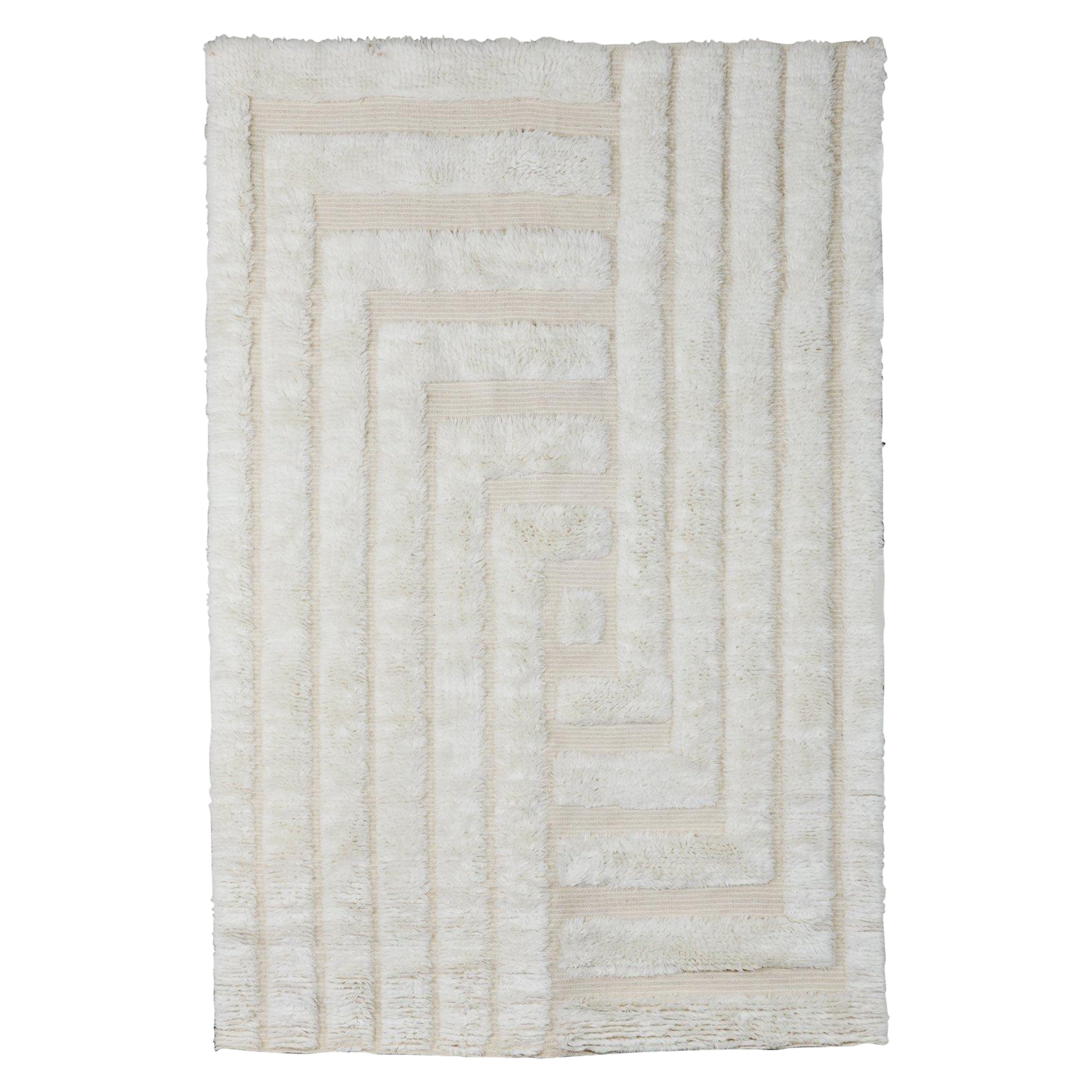 Le tapis DD Shaggy Labyrinth est tissé à la main et composé de 100% de laine. Il présente un motif unique car certaines parties du tapis sont tissées à plat et d'autres en poils hirsutes, ce qui lui donne un aspect unique grâce à son effet de