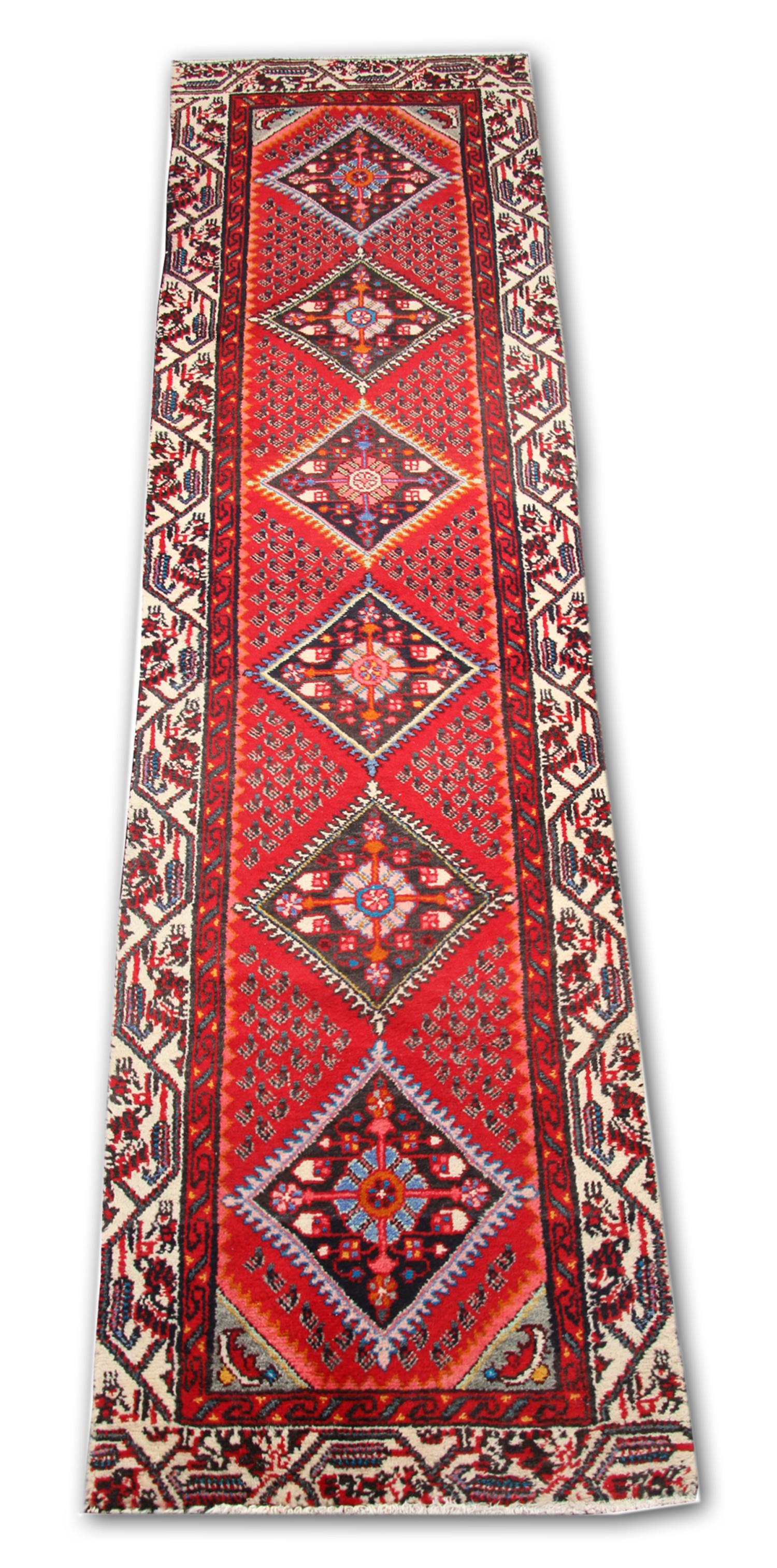 This vintage rug was constructed by hand with fine organic materials. Woven with a traditional design and colour palette. Featuring a rich red background and highly decorative medallion design through the centre and a repeat motif border. This