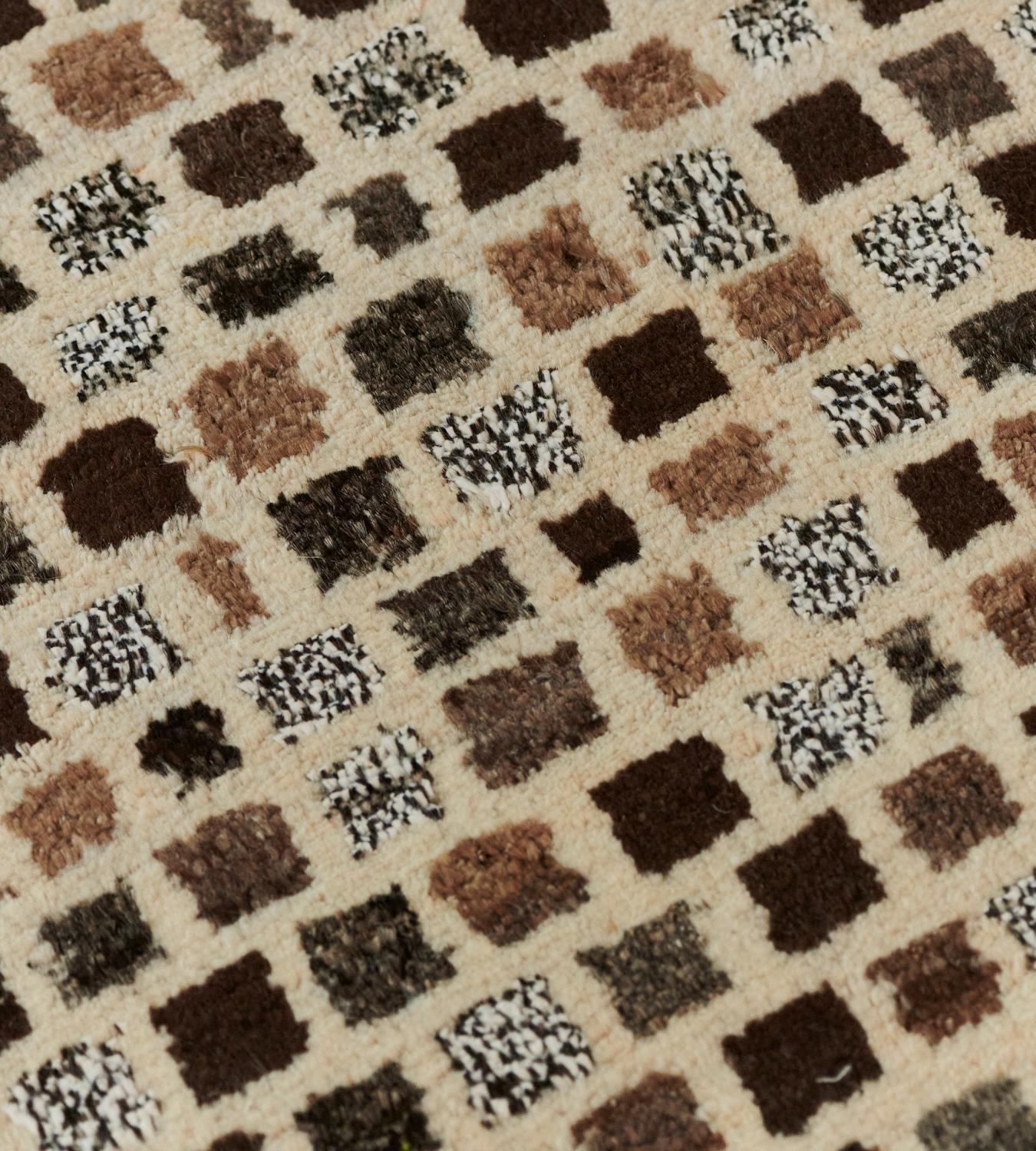 This hand-woven Turkish Deco rug has an overall field of mole brown, grey, and dark brown cells on a camel field.