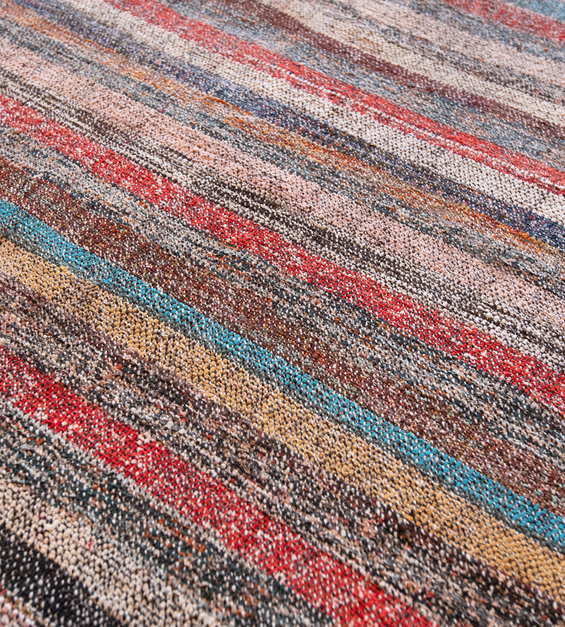 This handwoven flatweave Turkish carpet has a field of two panels joined together, with horizontal rows of polychrome stripes.