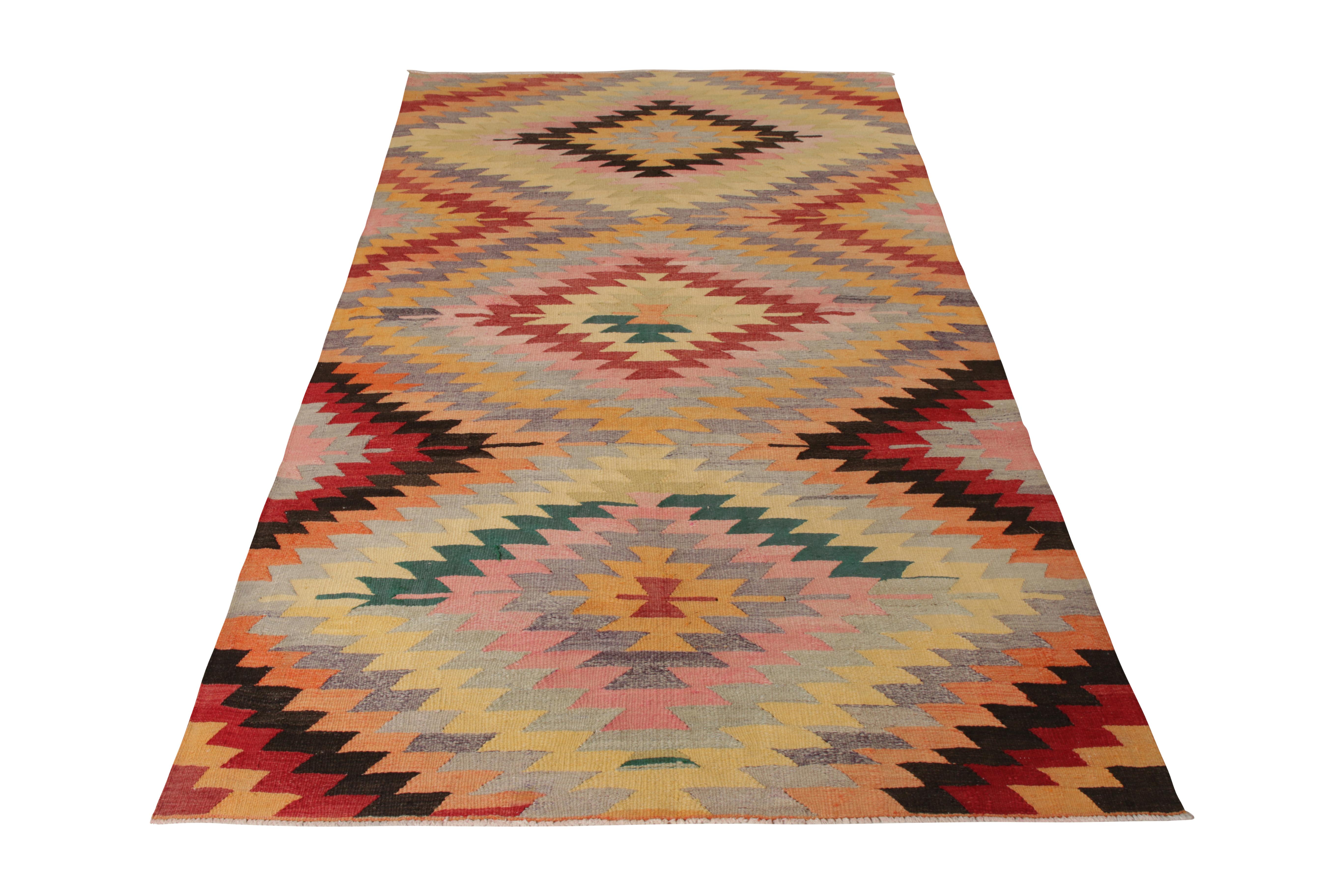 A 5 x 9 vintage Kilim rug of Afyon design lineage, handwoven in wool originating from Turkey circa 1950-1960. Enjoying vibrant, modern colorways for its age in notable red, pink, blue, and gold in this all over geometric pattern. Approachable with