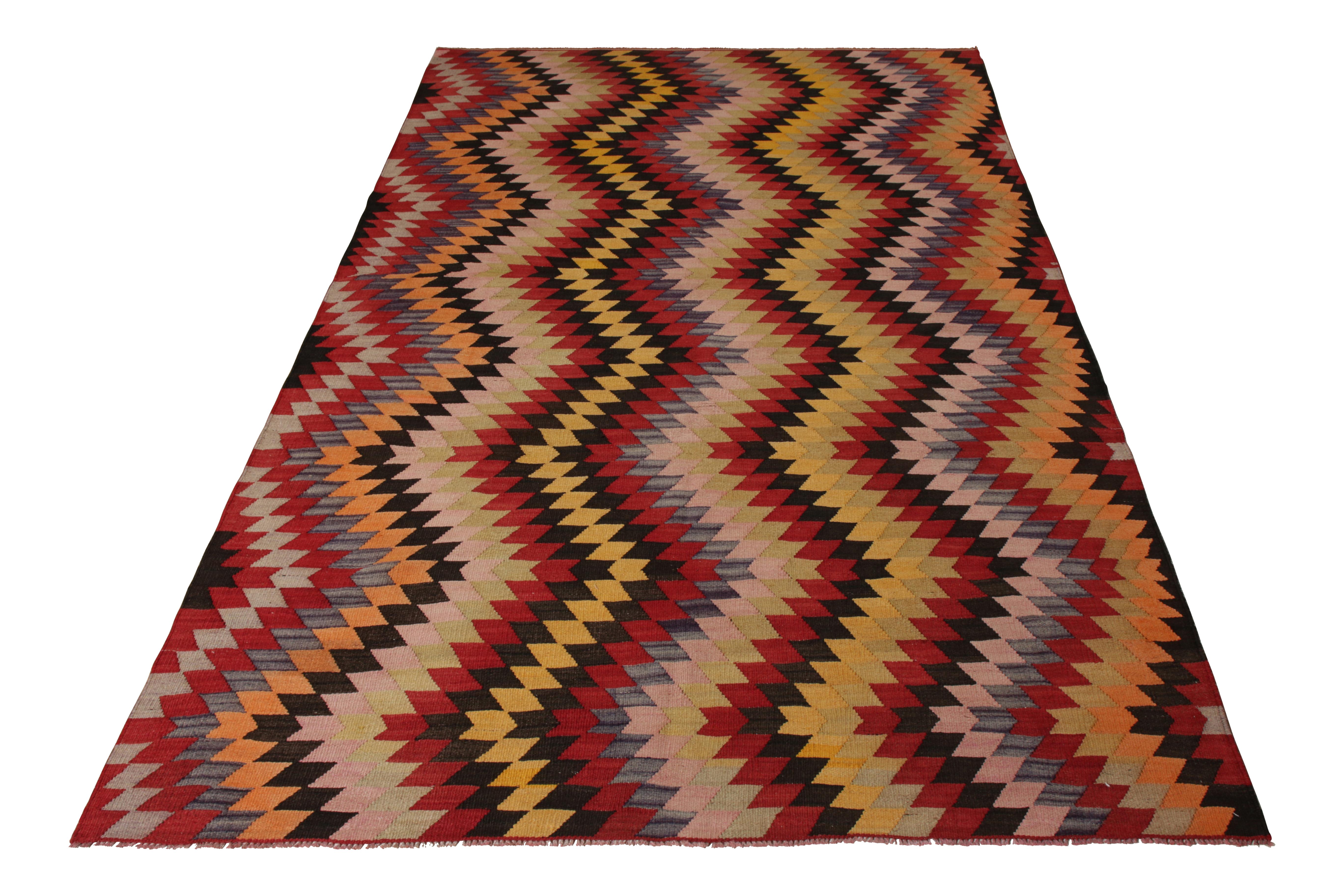 A 5 x 8 vintage Kilim rug of Afyon design lineage, handwoven in wool from Turkey circa 1950-1960. Enjoying a zig-zag Chevron pattern in vibrant stripes of red, gold-yellow, and pink among the playful multicolor hues. Meticulous in its geometry,