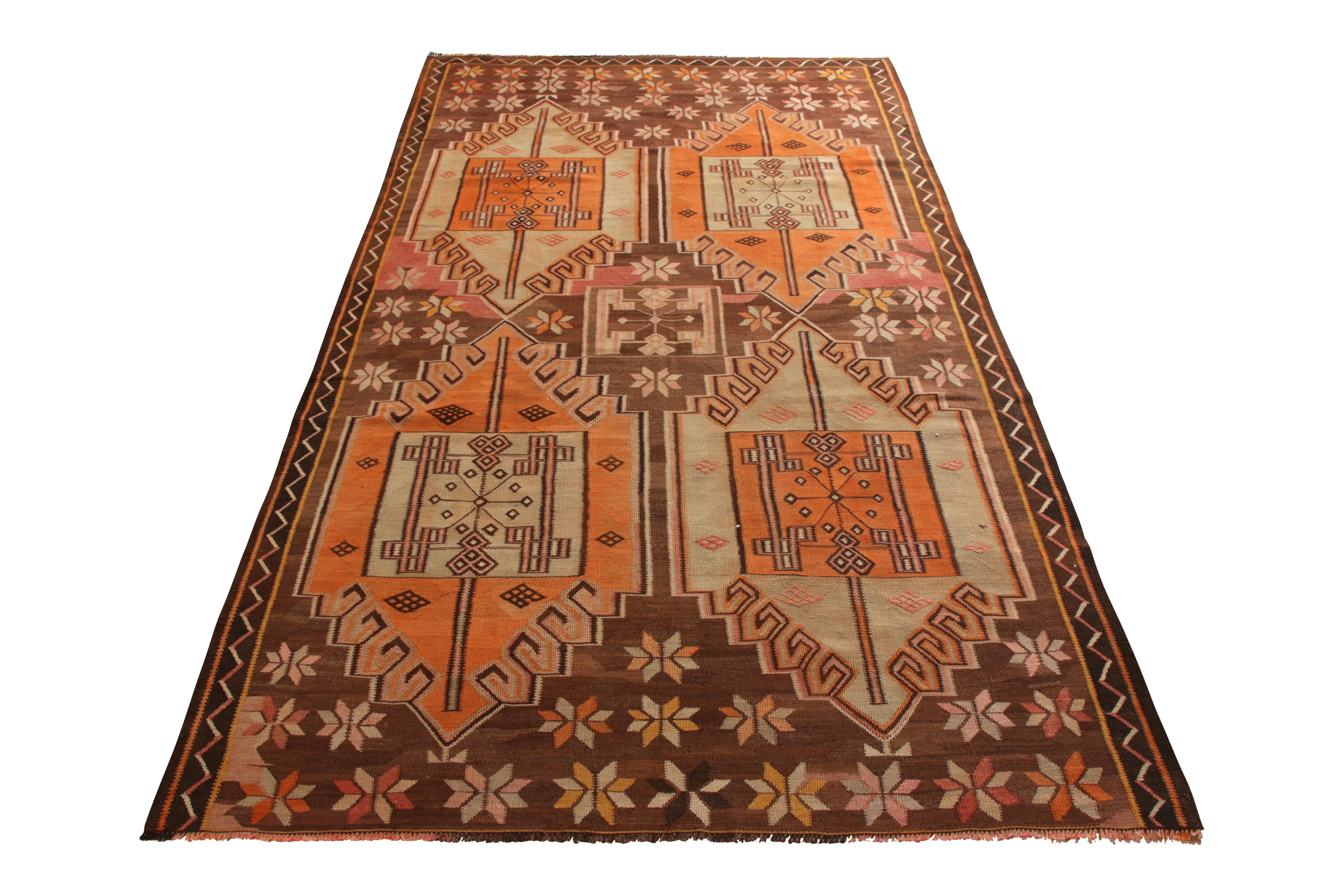 A 5x9 vintage Kilim rug of Kars design lineage, handwoven in wool originating from Turkey circa 1950-1960. Enjoying a graphic medallion pattern in a unique play of brown with orange and blue among the playful accenting colors. Further sporting good