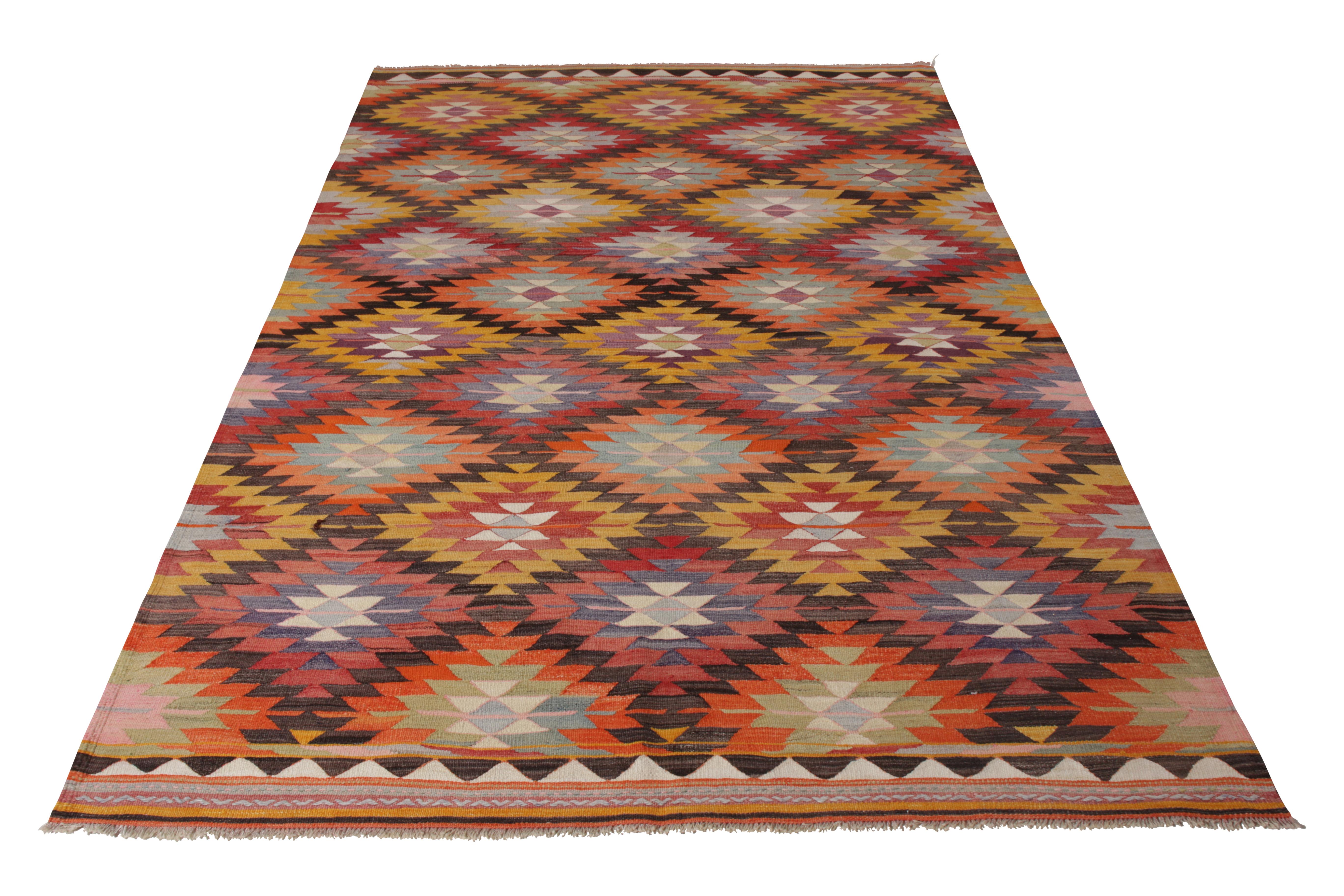 A 6 x 9 vintage Kilim rug in handwoven wool, originating from Turkey, circa 1950-1960. Enjoying warm orange and gold in the wide-spanning tribal colorway pallet throughout the all over geometric pattern. Inviting in its repetition, arresting in its