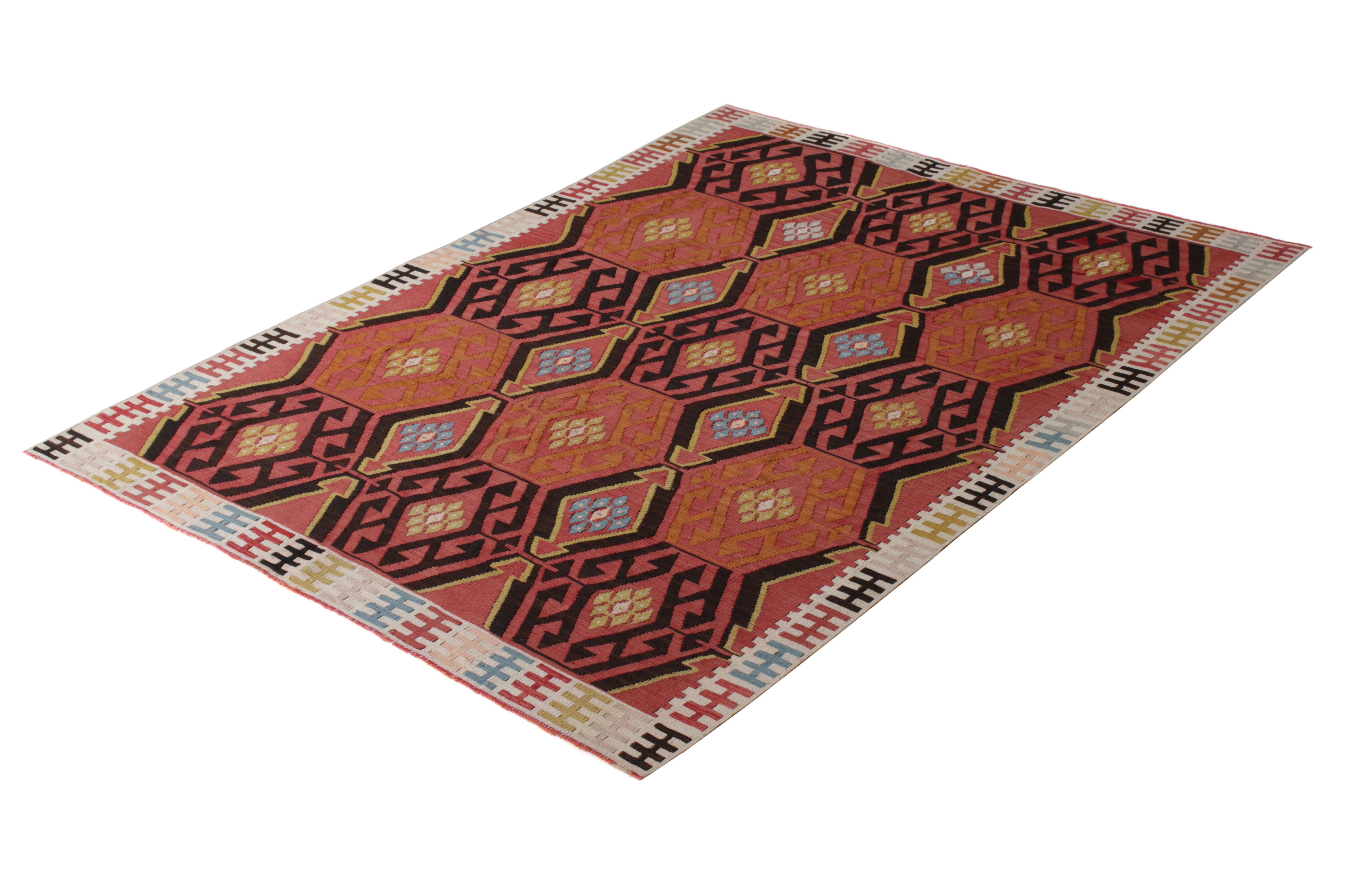 Handwoven in a wool flat-weave originating from Turkey, circa 1950-1960, this vintage Kilim rug connotes a mid-century take on Turkish tribal Kilim rug designs in a rich pallet of red, brown, and black. Interwoven accents of whimsical colors bring